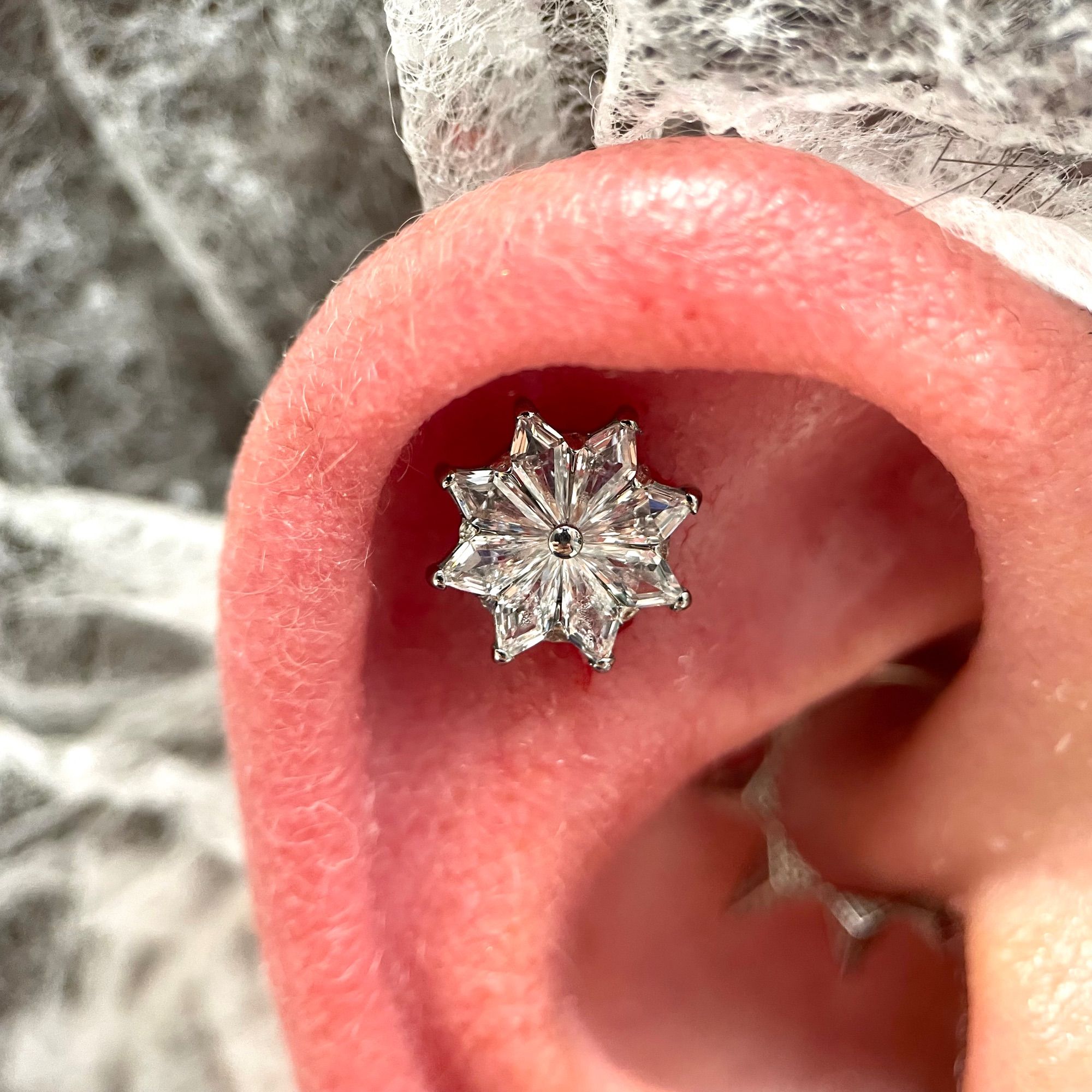 Piercing Flat réalisé avec un bijou strass en forme de flocon de neige.