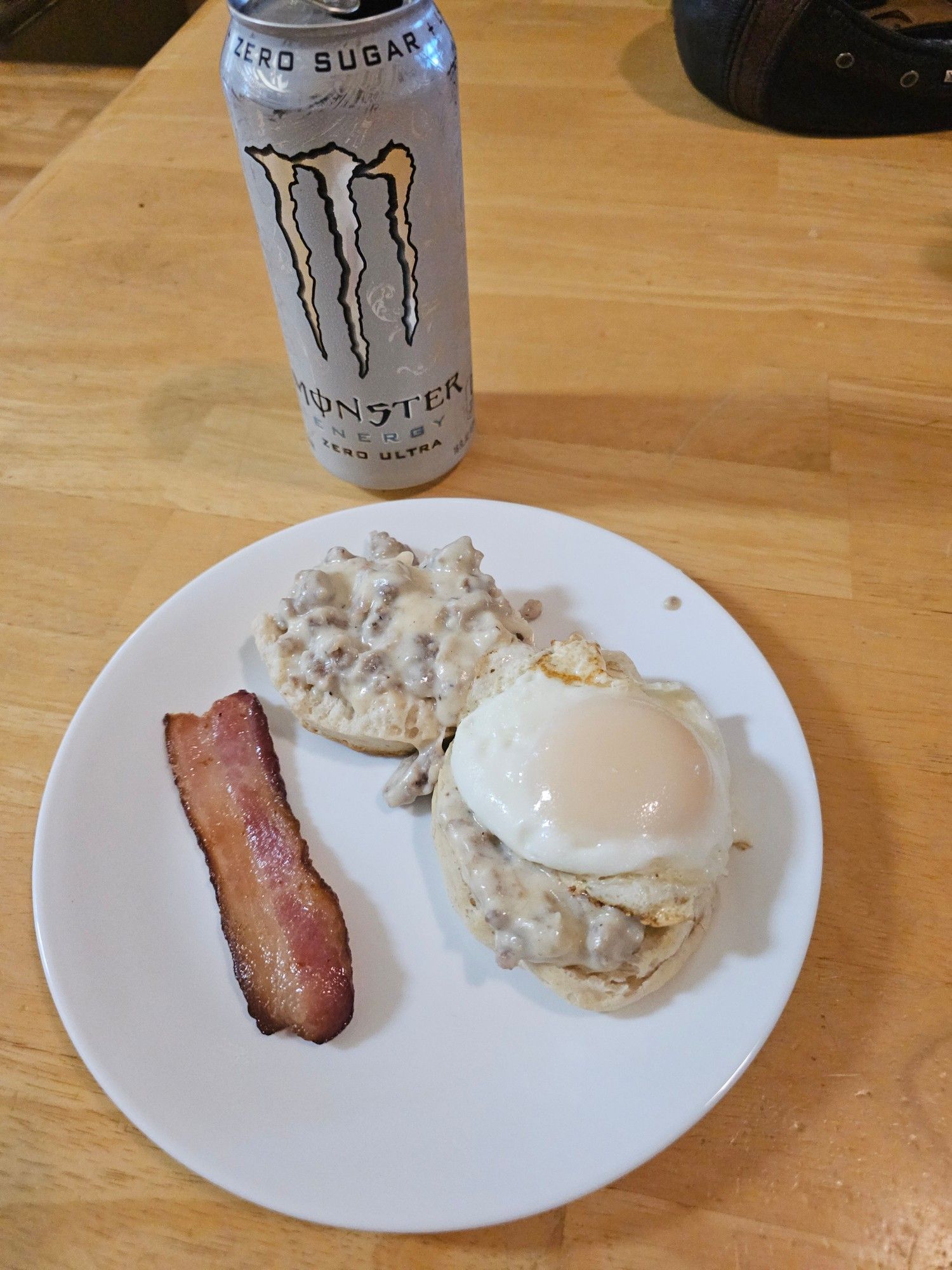 One fluffy American biscuit, split, under some sausage gravy and a basted egg. One half-strip of thick cut bacon on the side. 