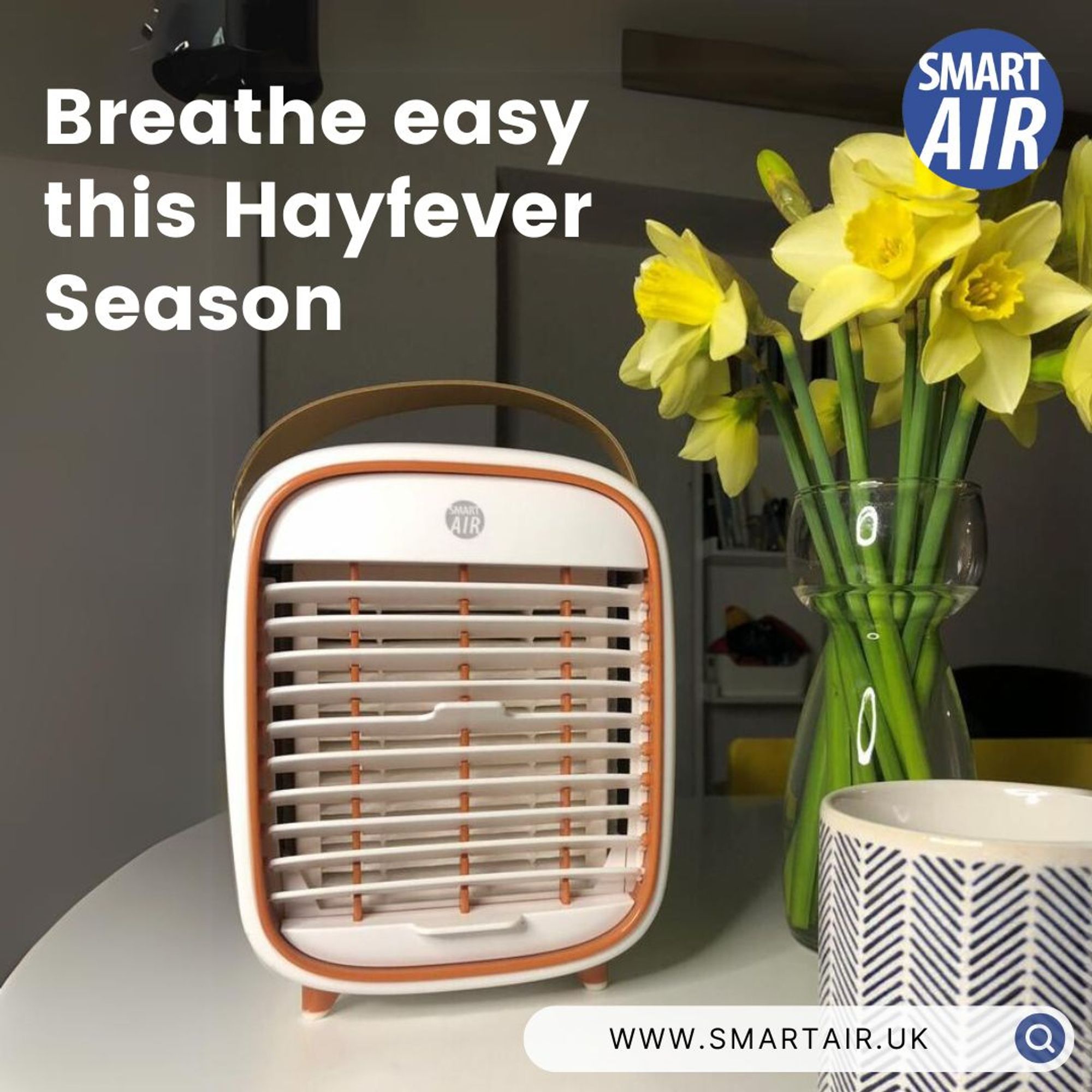 Image shows the QT3 travel air cleaner from www.smartair.uk on a table with a mug and a vase of daffodils. Text reads: breathe easy this hayfever season