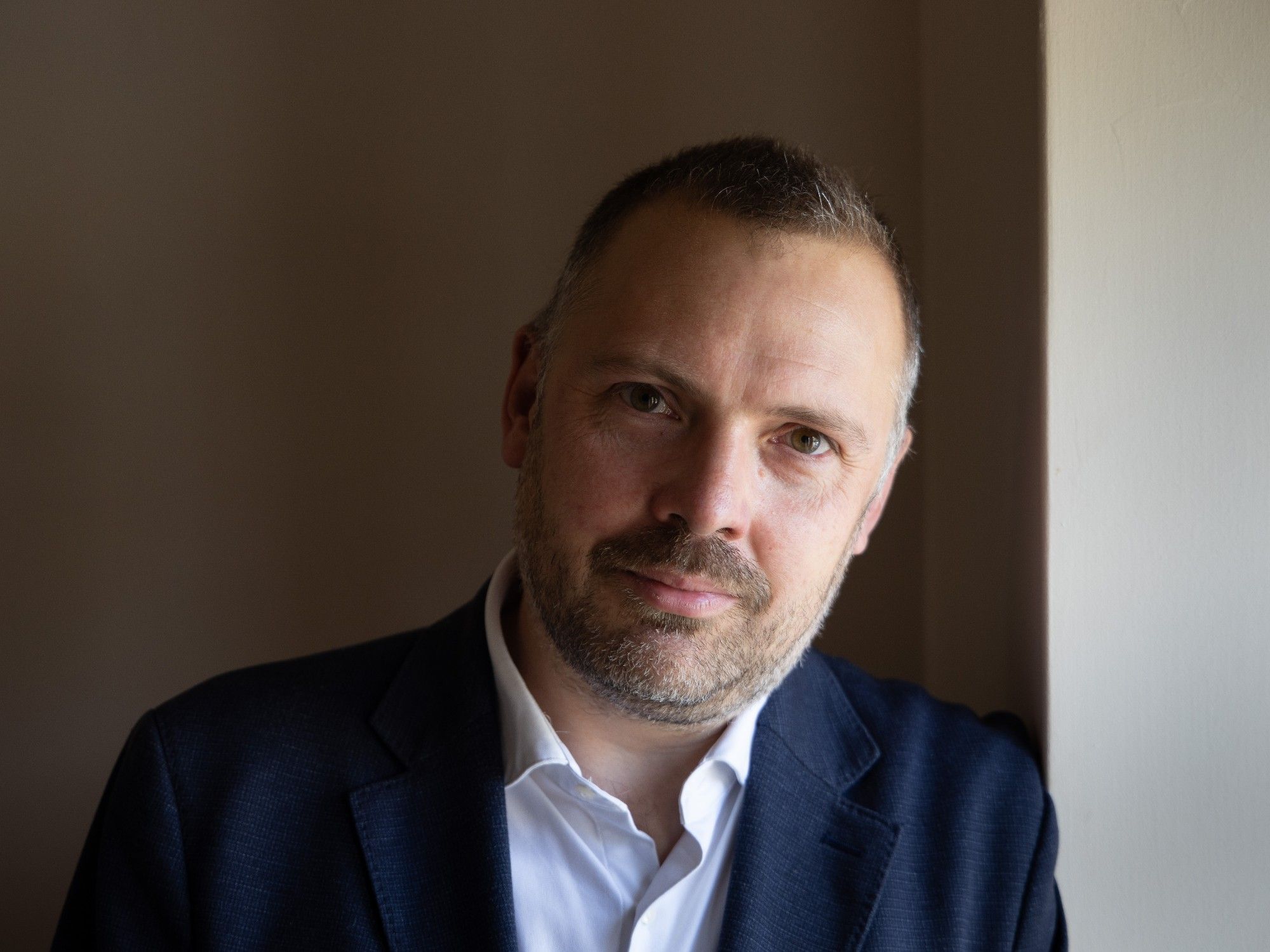 Man in dark blue suit looking directly at the camera