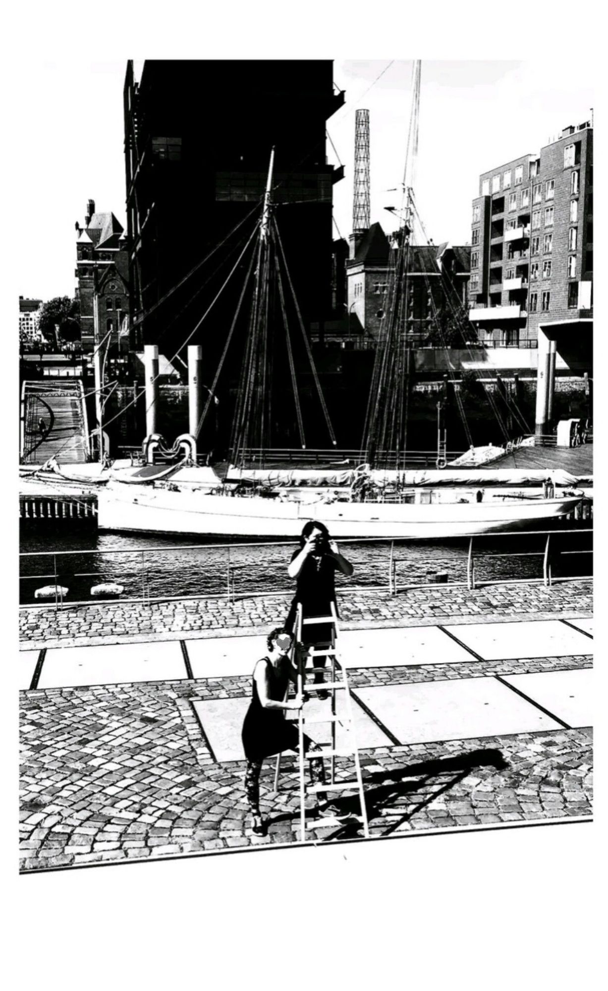 Stark grafisches Foto in der Mitte eine Leiter auf der eine Frau steht die fotografiert die Leiter wird von einer anderen Frau gesichert im Hintergrund ein Segelboot am fleet sowie Neubau Architektur. Es ist sommerlich