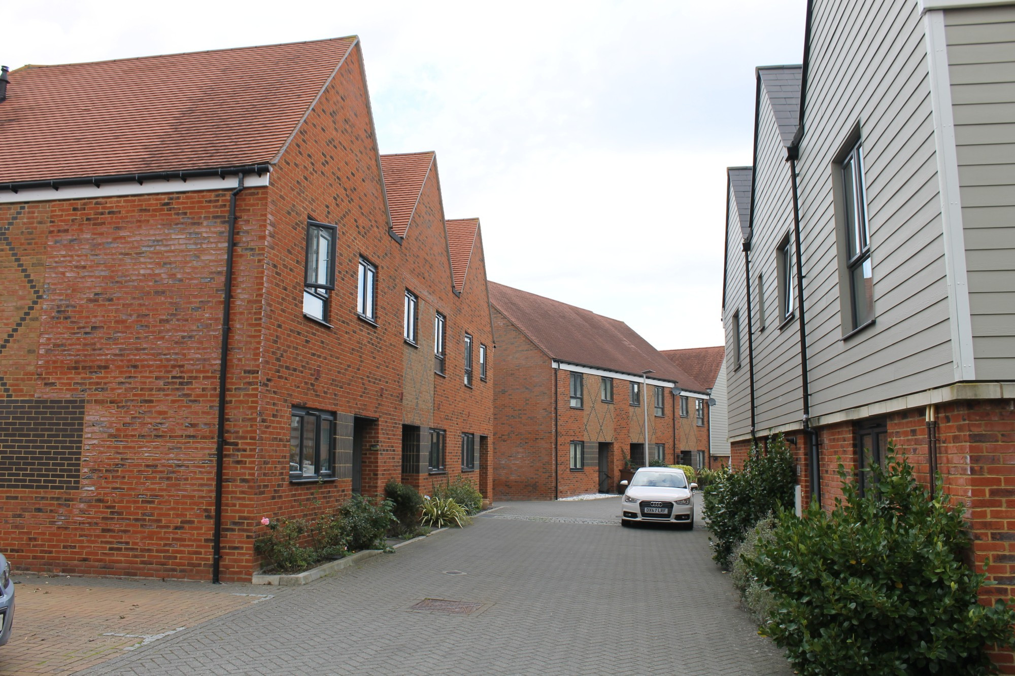 a mews street with shared surface and lined by 2 storey mix of red brick and weatherboarded homes