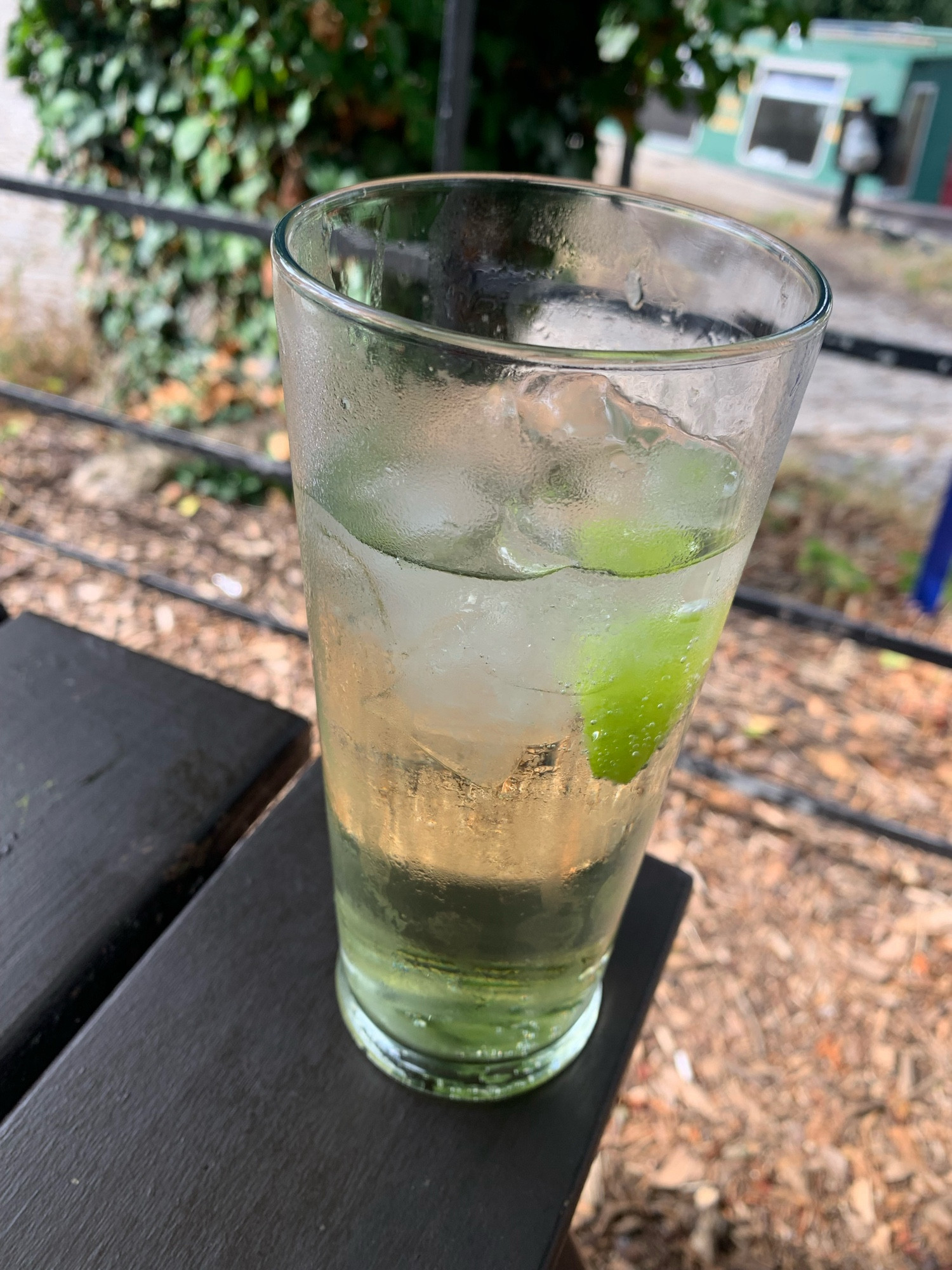 Pint glass of soda and lime outside on a pub table.