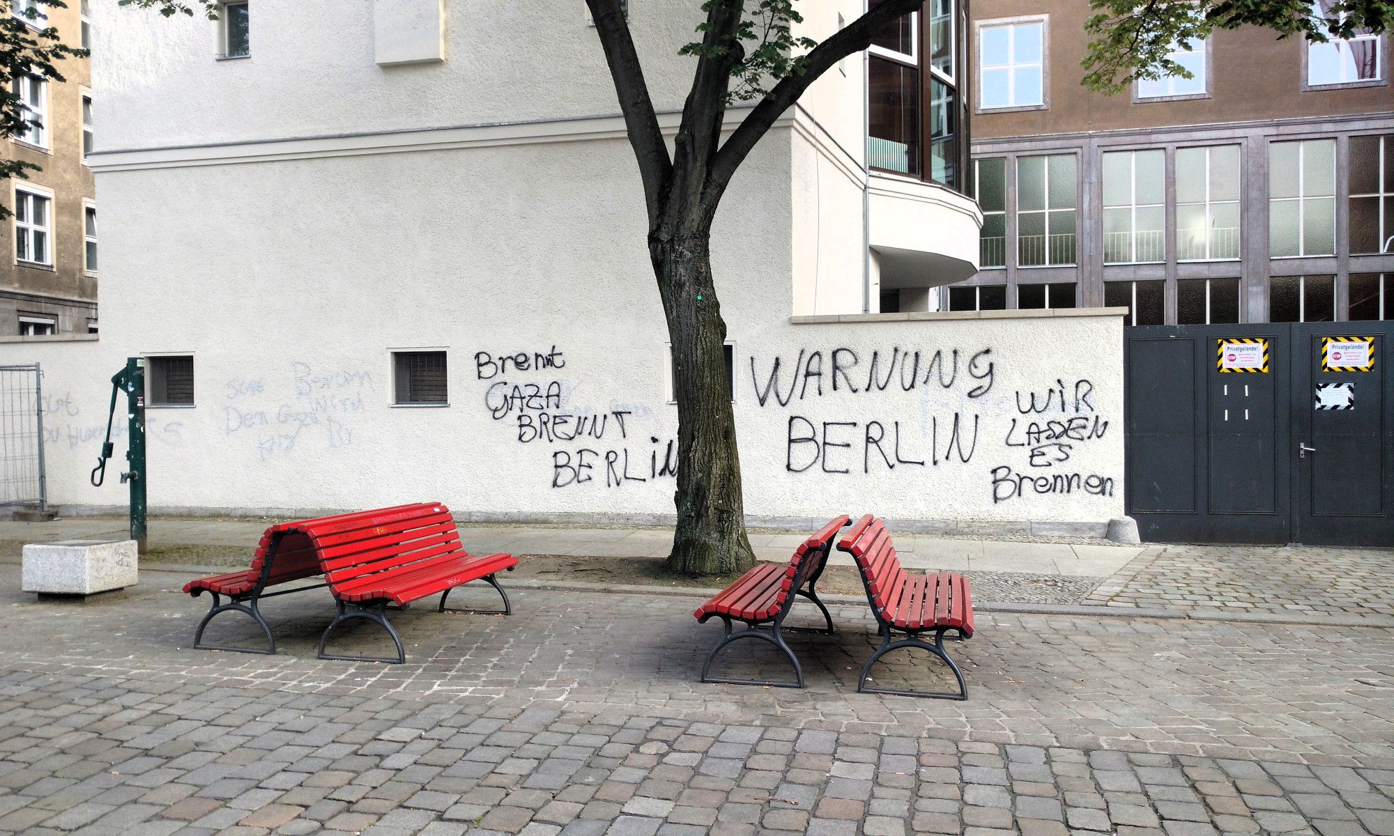 Auf dem Foto eine weiße Hausfassade, darauf steht mit schwarzer Farbe "Brennt Gaza brennt Berlin" und "Warnung Berlin Wir lassen es brennen".