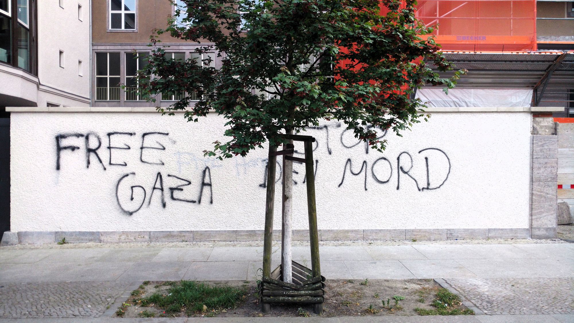 Auf einer weißen Hauswand steht "Free Gaza Stop den Mord"