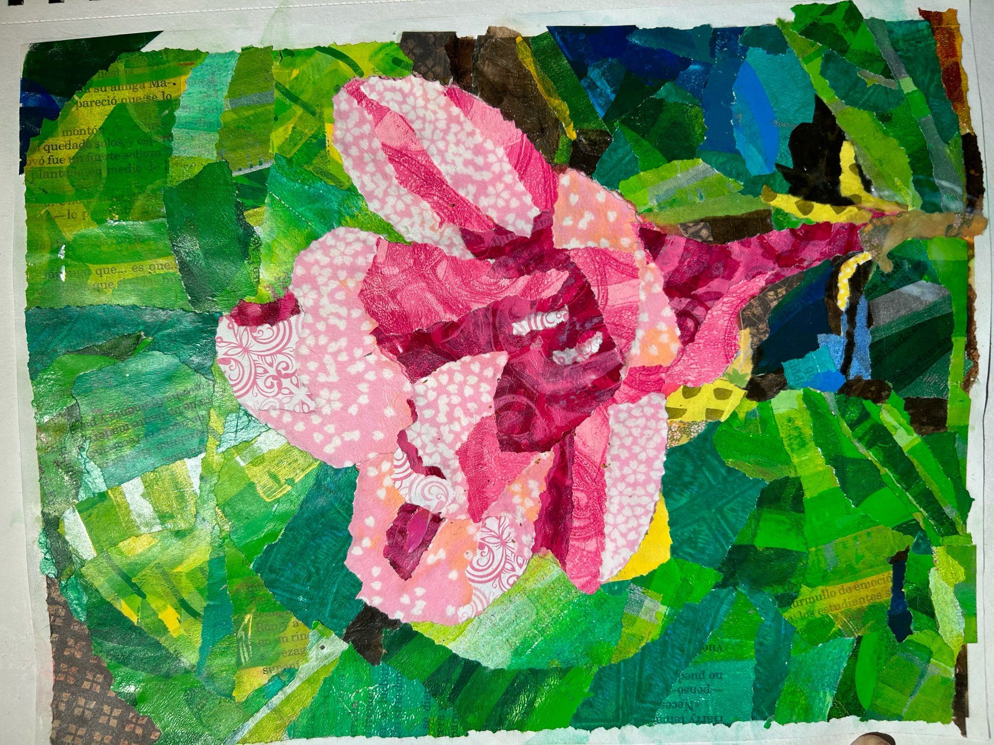 Paper collage of a flower in pinks on green leaves, with little bits of brown background showing through.