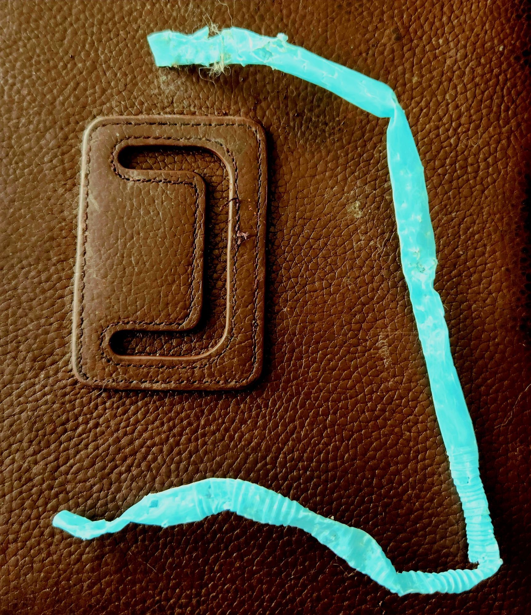 A turquoise drinking straw that has been chewed, twisted, and bent.