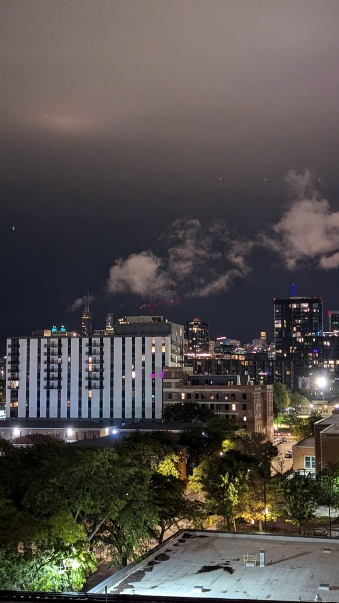 A view of the Chicago Loop skyline, with the skyscraper formerly known as the John Hancock behind a new condo, with what appears to be smoke spraying from near the building's antennae