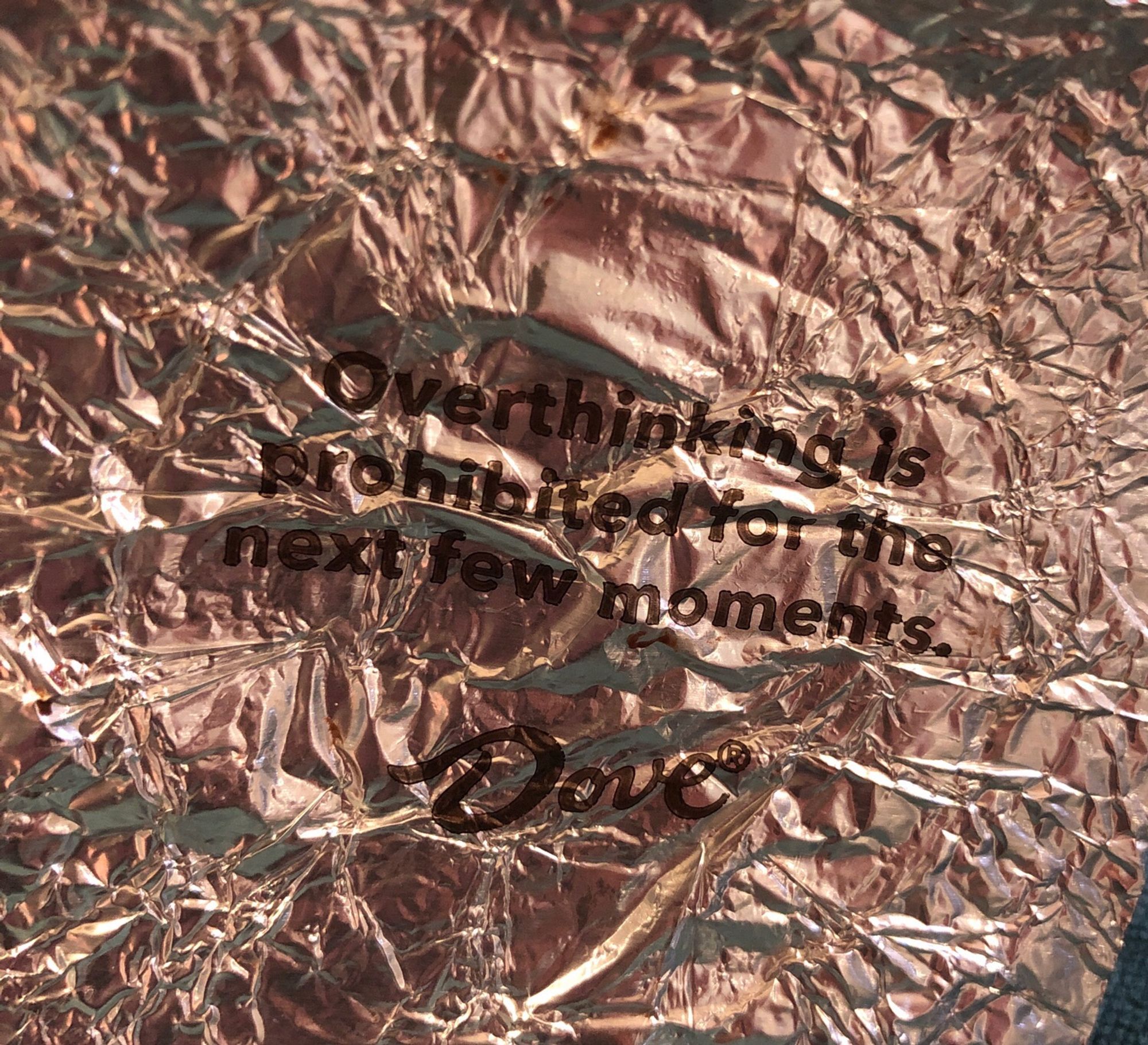 A foil wrapper from a Dove chocolate with the text: “overthinking is prohibited for the next few moments”