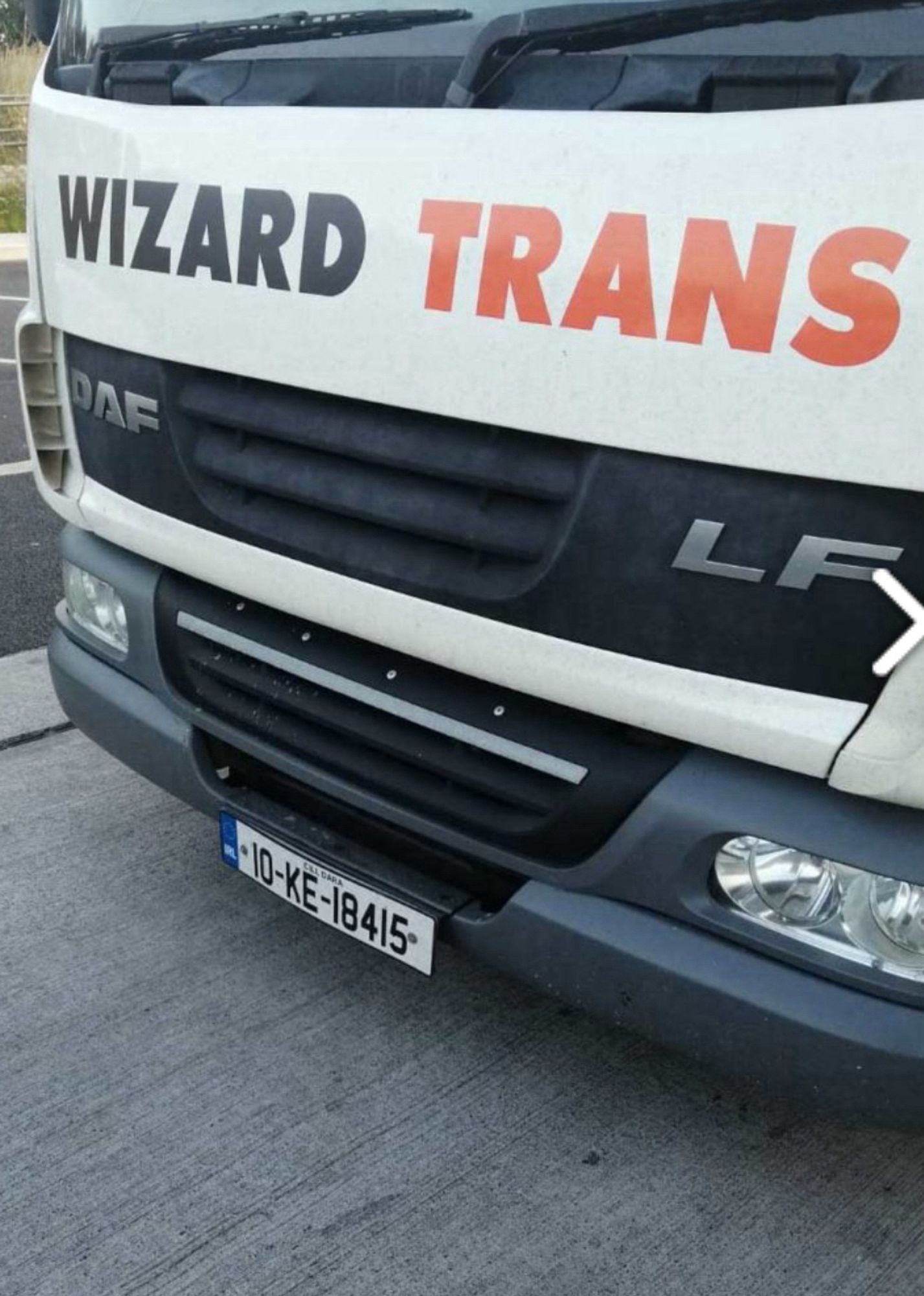 The front of a white truck with a logo saying “wizard trans”