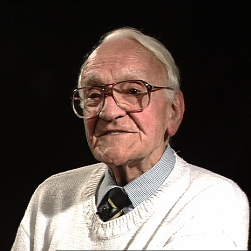 Stanley Unwin, looking rather dapper in a grey shirt, striped tie and white jumper.