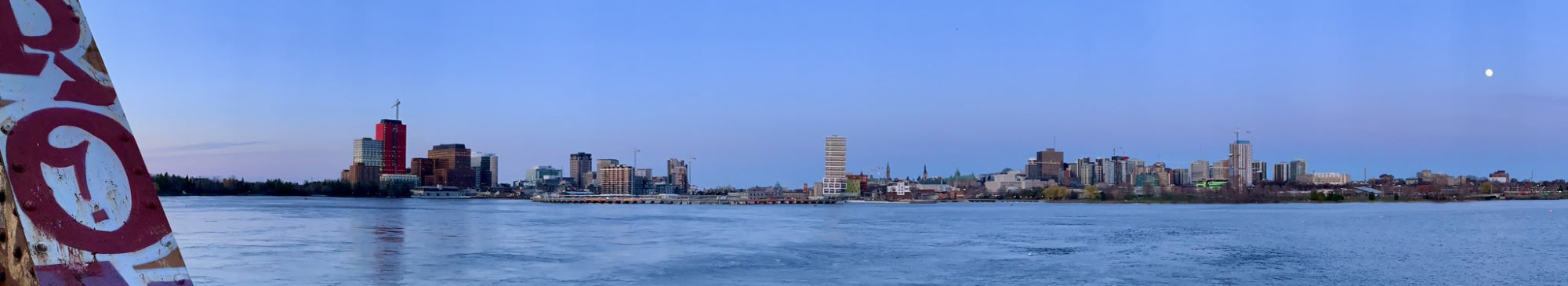 Panoramic view of Ottawa and Gatineau from the William Commanda Bridge, with a glimpse of graffiti-covered bridge girder at left, and the almost full moon hanging over the whole scene at right. Dusk is setting in and the Belt of Venus is sweeping in from the east.

Still kinda suspicious of the moon tbh. Sure it's on the opposite side of the sky from the sun now, but what is it going to get up to next?