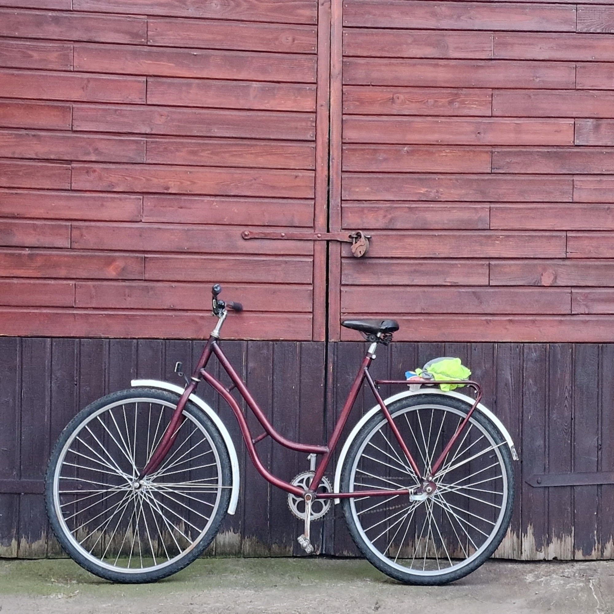 My father in law's bicycle: a old bike from the 80s very rustic looking sitting upright against the doors to an old barn
