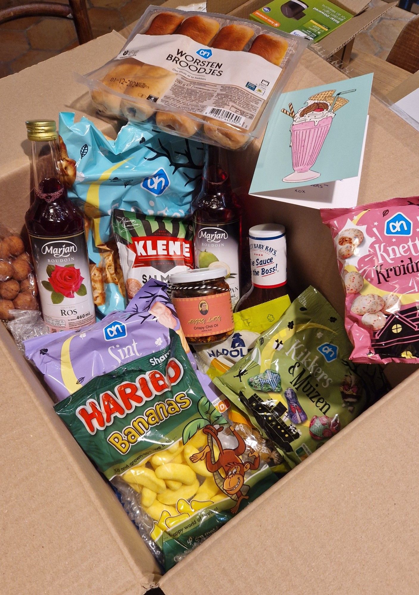 A large box of treats including Dutch Sinterklaas candy, rose and pandan syrup, Haribo bananas, worstenbroodjes and more.