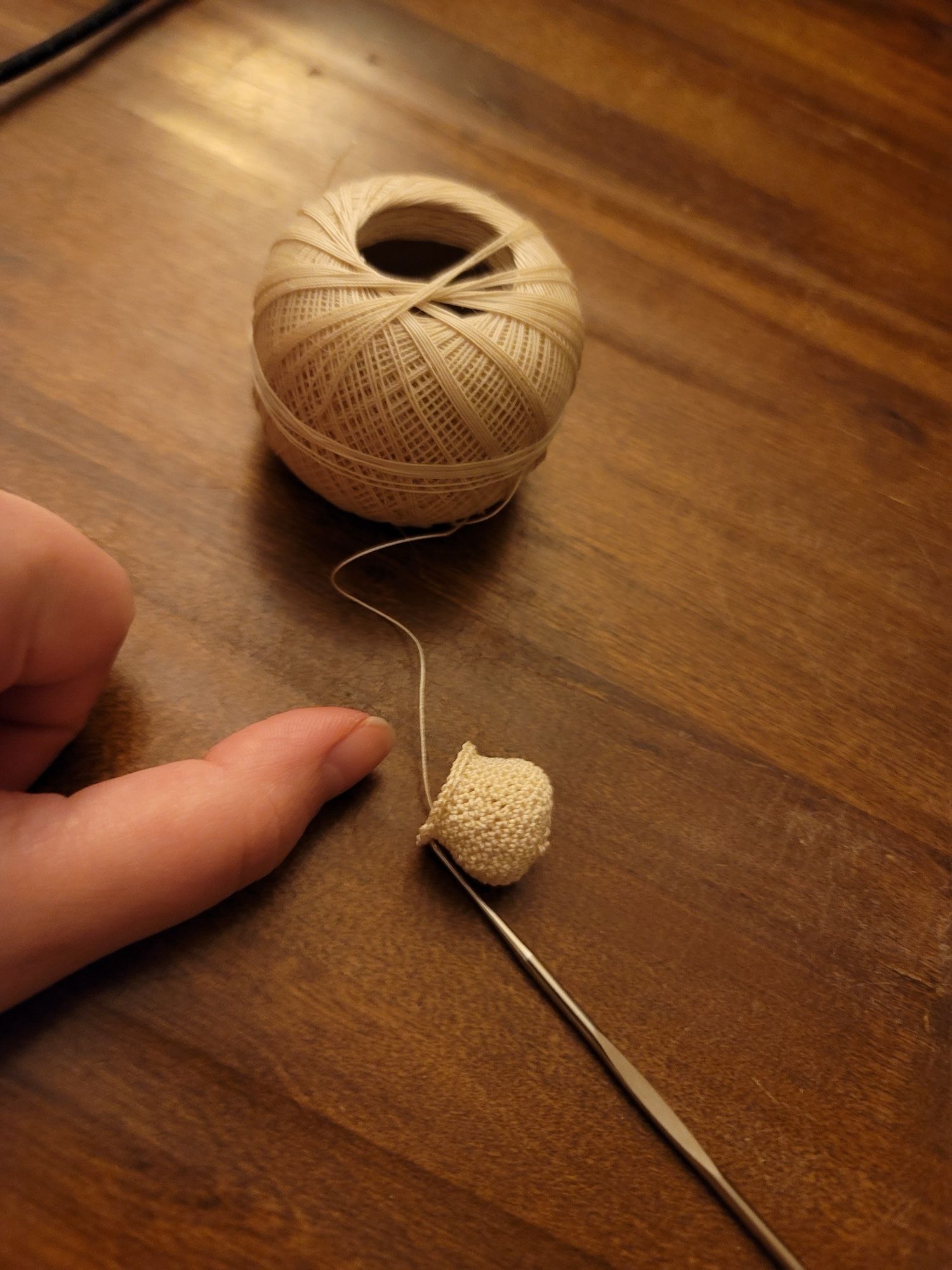 A piece of in-progress micro crochet the size of a thumbnail