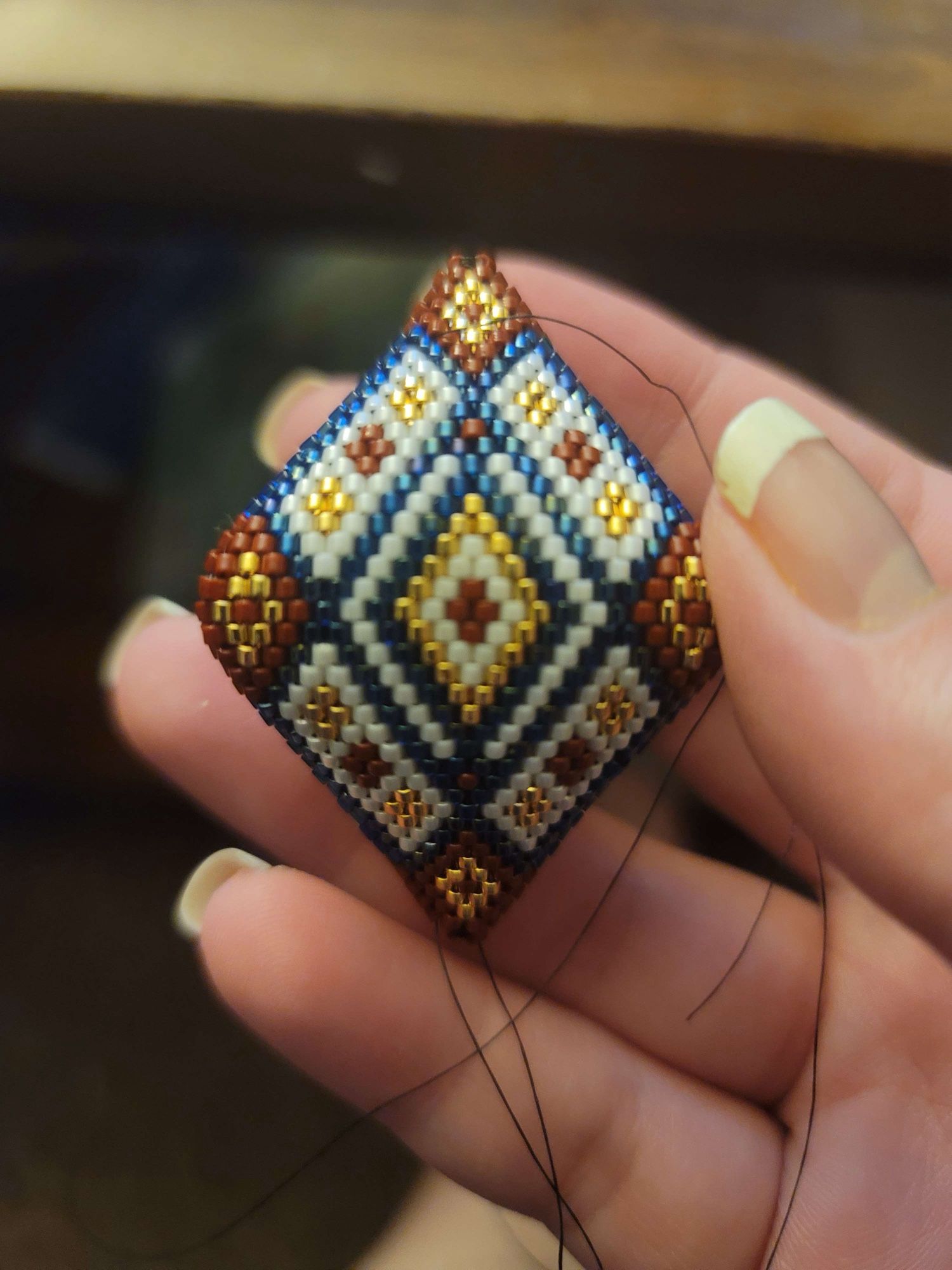 A small 3D beaded ornament in red, blue, white, and gold