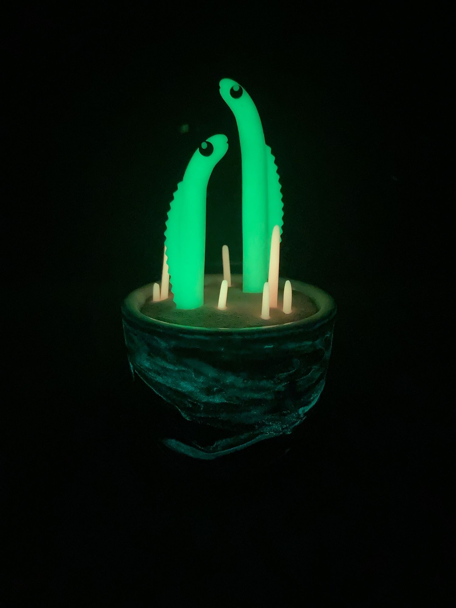 The previous sculpture in the dark, revealing the eels and coral glowing. Swirls on the pot also glow.