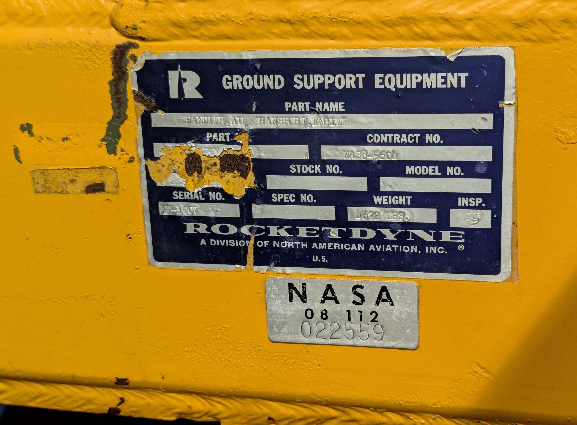 Black Rocketdyne label and silver NASA label on the yellow strut of a rocket engine cradle