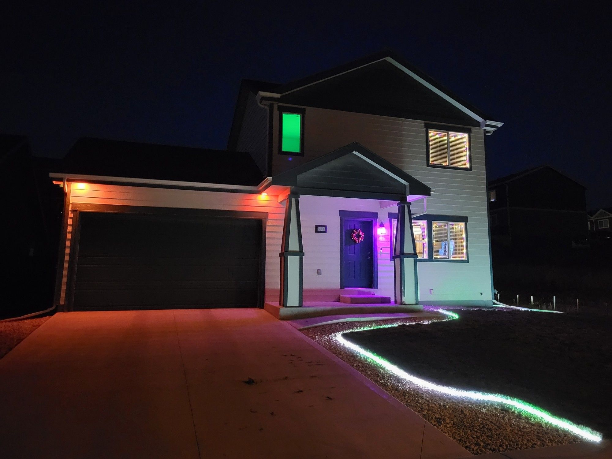 My house at night with several different colors of Halloween-y lights.