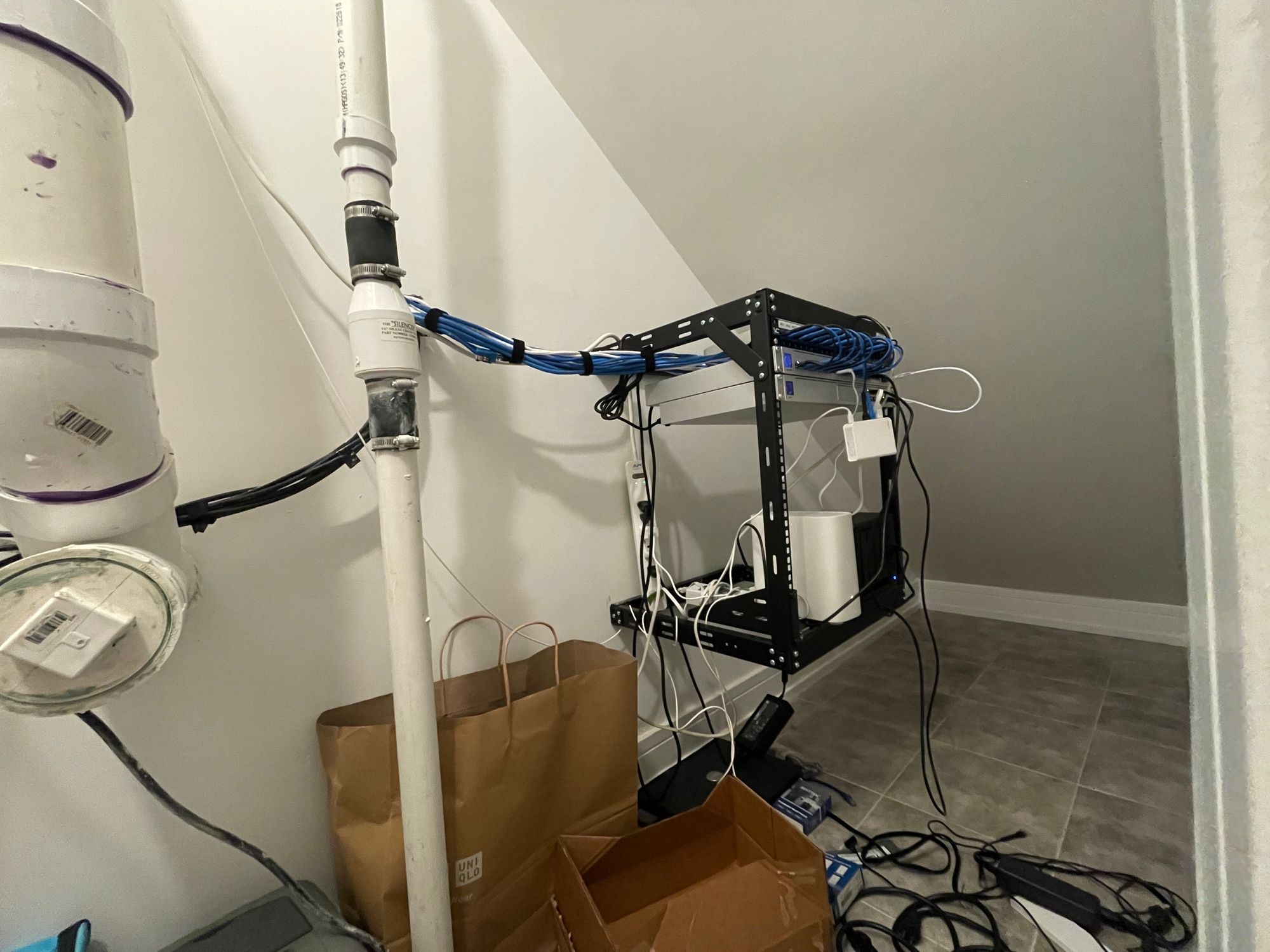 A sump pump next to a server rack that has a 24 port managed switch, a unifi dream machine pro, an AT&T fiber gateway that cannot be bypassed, a NAS box with nothing on it, and a shitty GLiNET router used as a vpn device for two modified Japanese arcade games. 