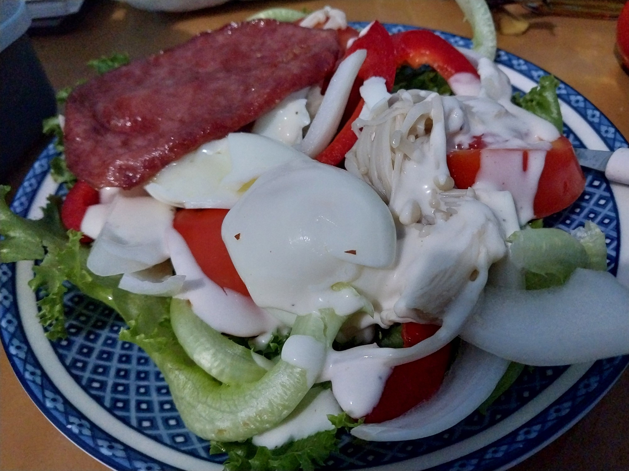 Homemade salad comprised of lettuce, tomato slices, mushroom, egg, and smoked beef.