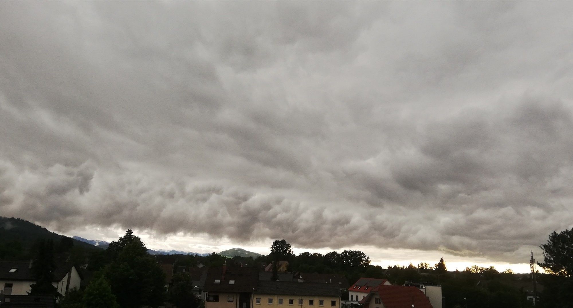 Im unteren Bildrand Häuser und Bäume, dahinter tiefhängende Regenwolke