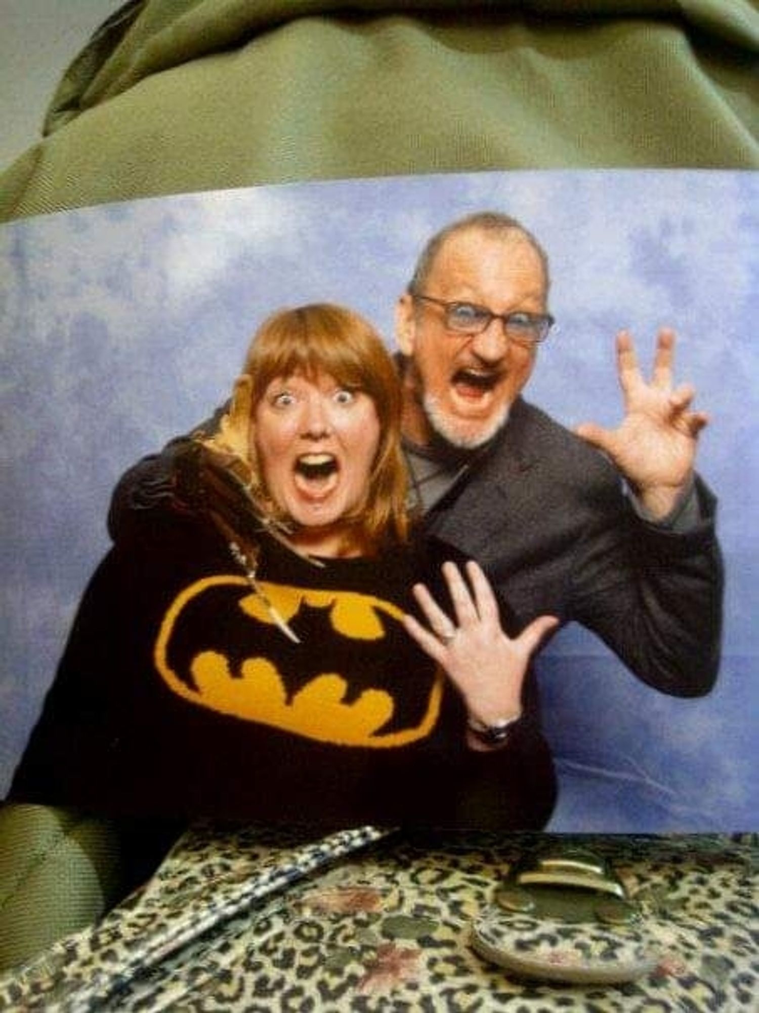 A red haired woman in a batman jumper is acting scared as Robert Englund places a metal claw at her throat