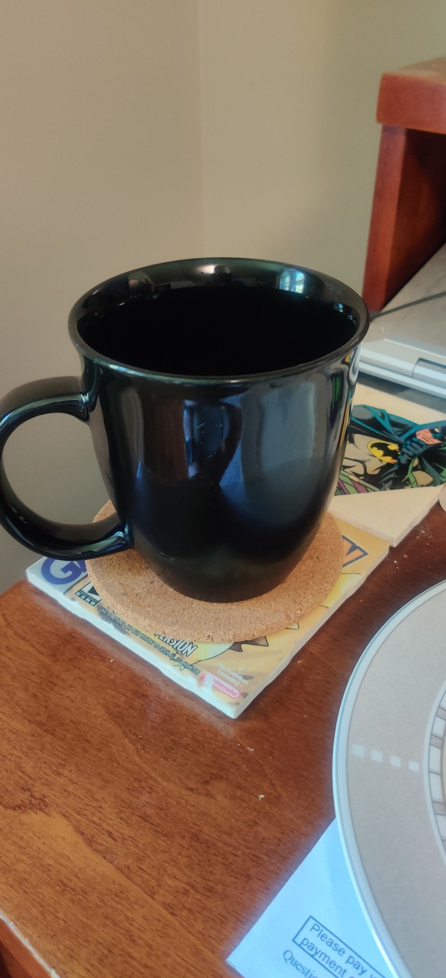 A black coffee mug containing coffee and coke.