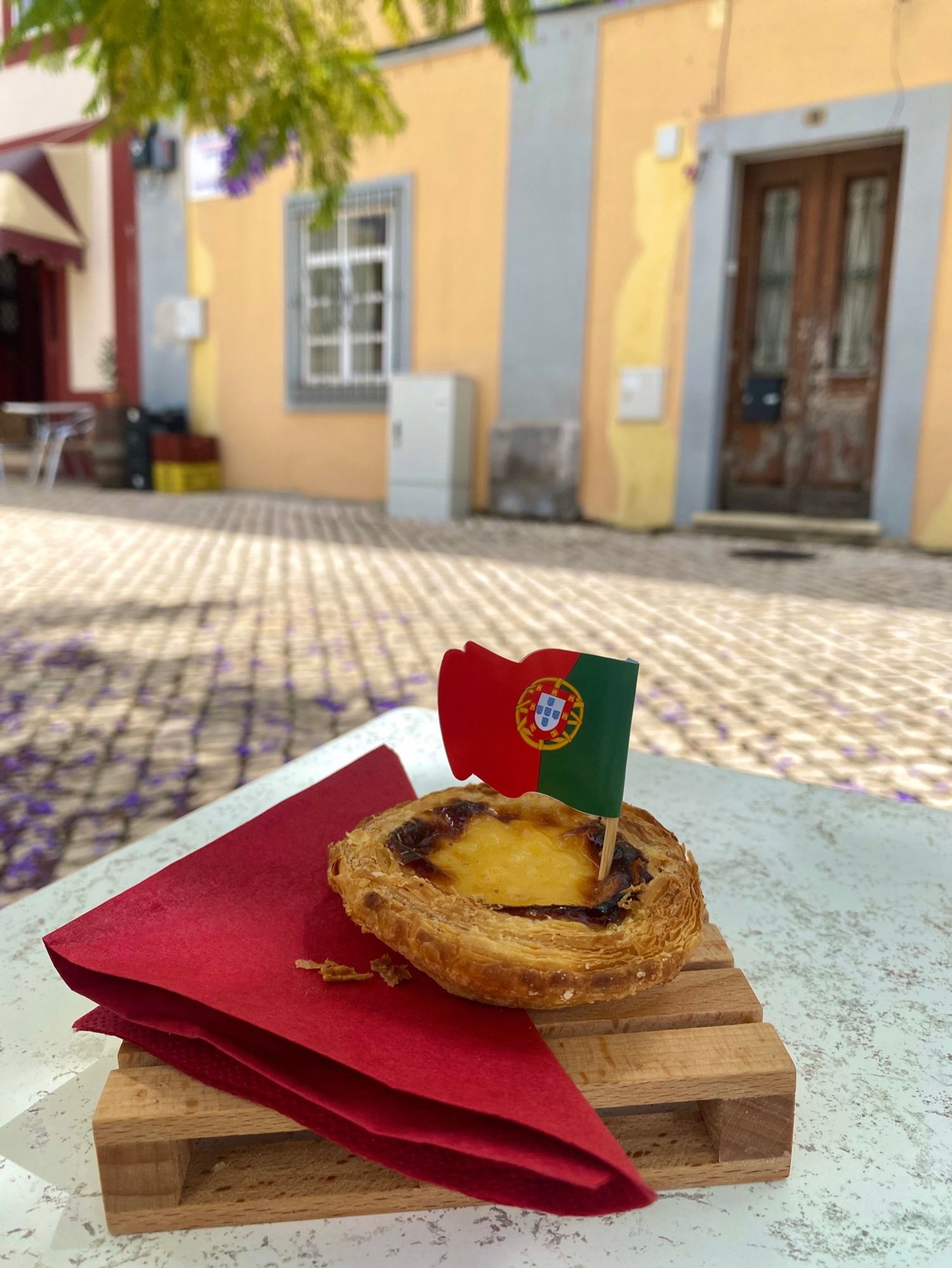 A photo of a what looks like a custard tart on a mini crate with a Portuguese flag in it