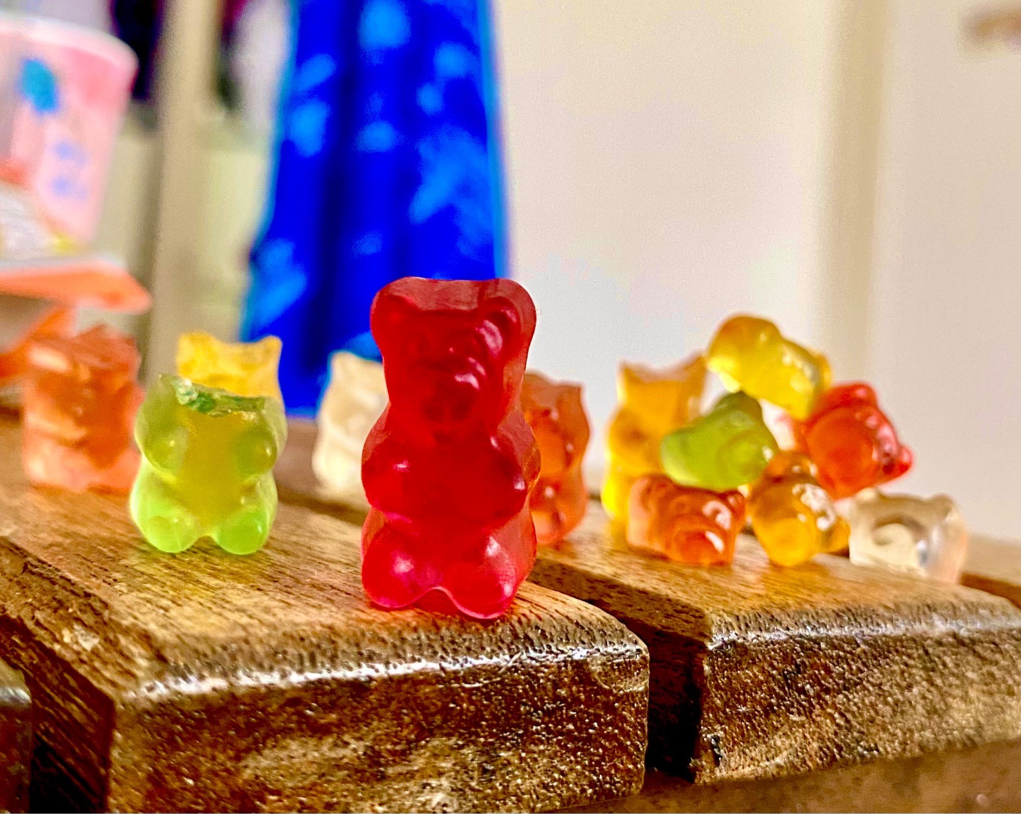 A red gummy bear with 8 gummy bear heads stacked behind him. And numerous headless gummy bears standing behind him. He looks indifferent, what an asshole. mirbear