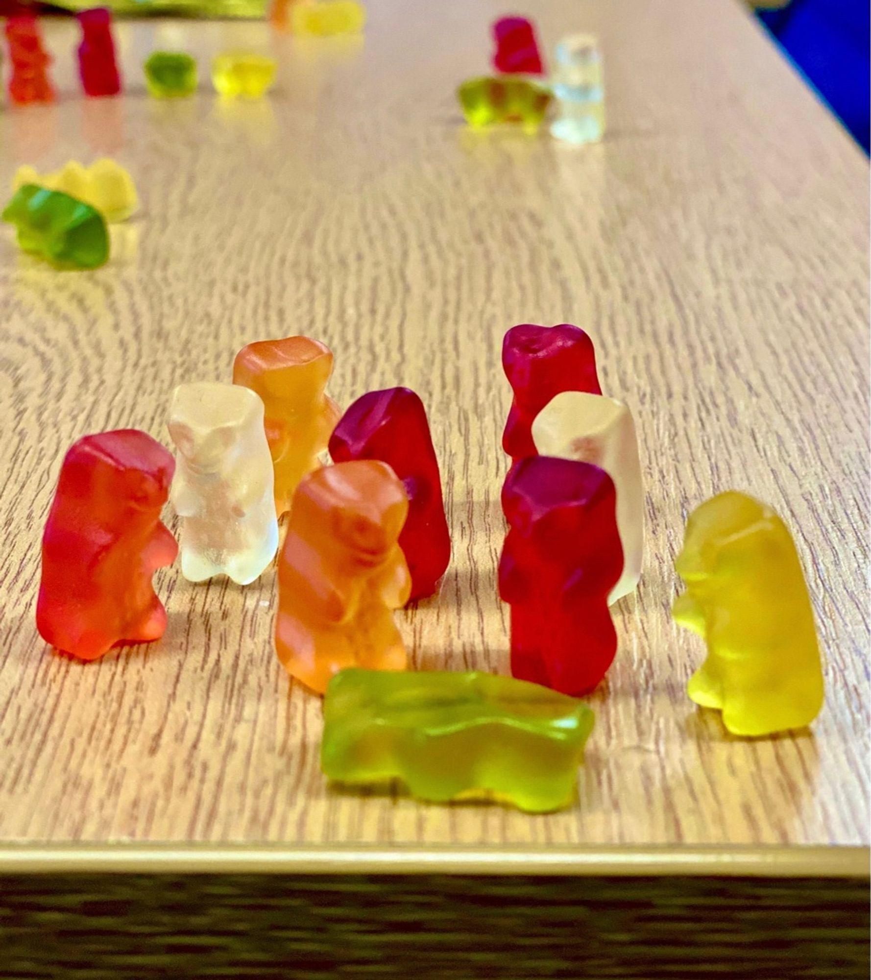 9 colourful gummy bears standing over one dead gummy bear lying face down.
They are standing on a table. The betrayal is palpable.