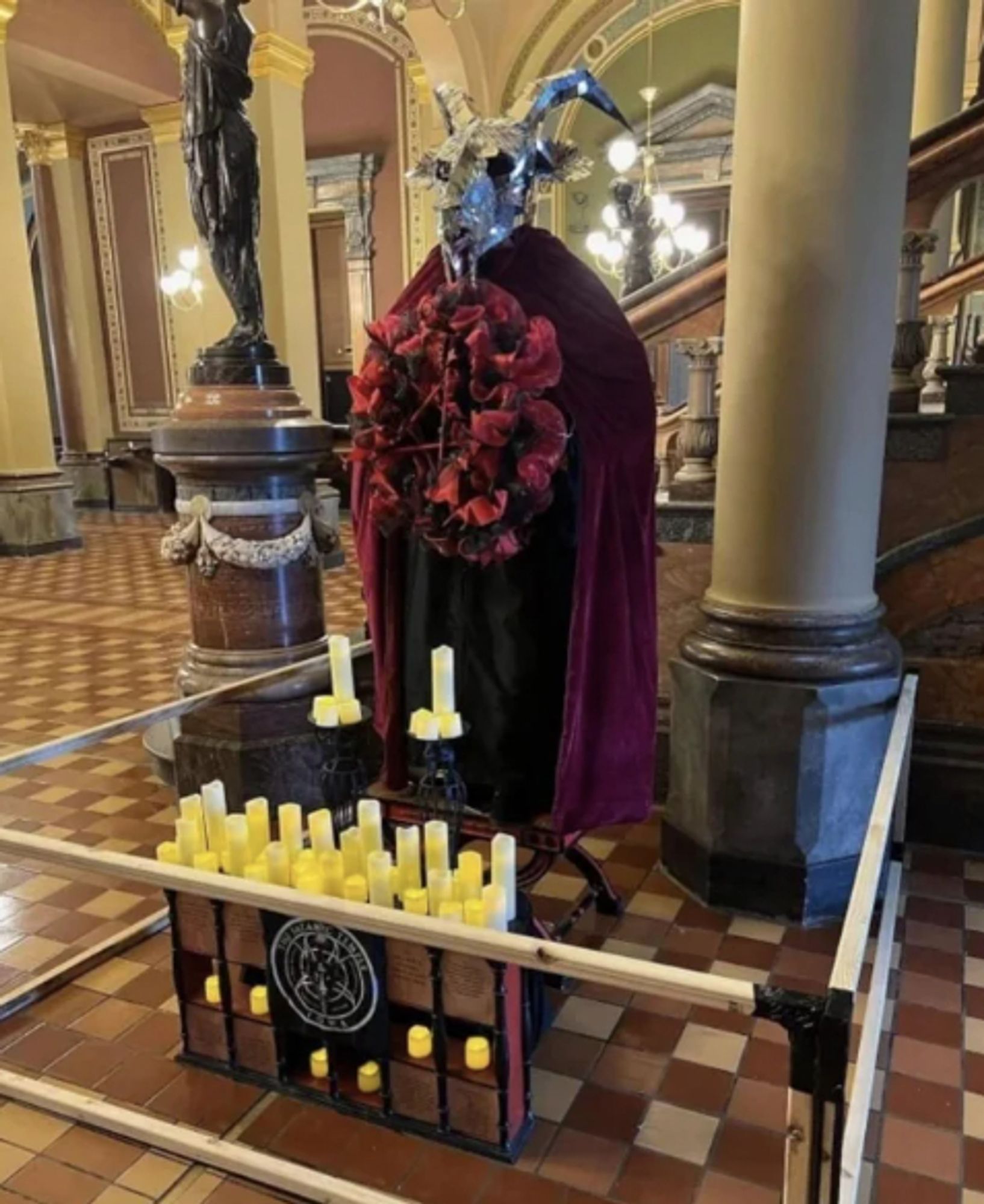 a large statue thing wearing a cloak with a sparkly silver goat head and kinda spooky candles in the halls of iowa states capital