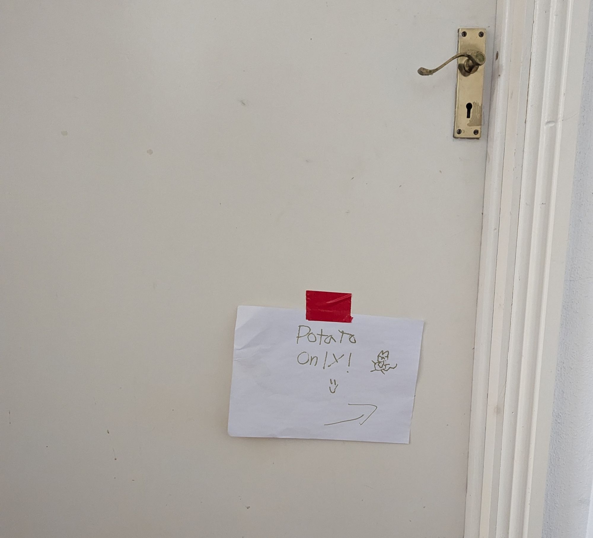 A closed door with a sign taped onto it. The sign reads "Potato only" referring to the nickname we gave for our cat, Manchego.