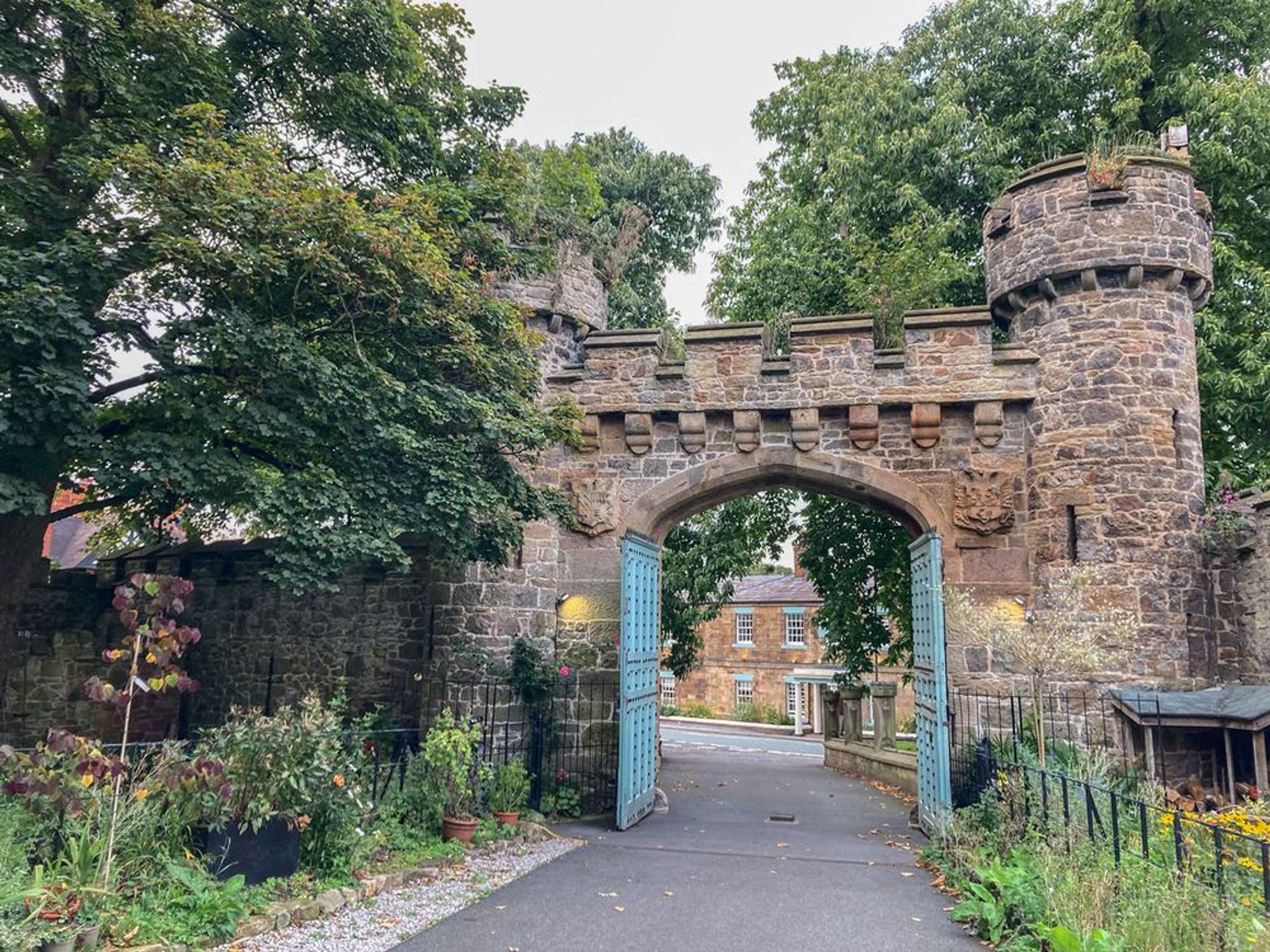 A view of crenellated gates with turrets. They are built with grey stone. 