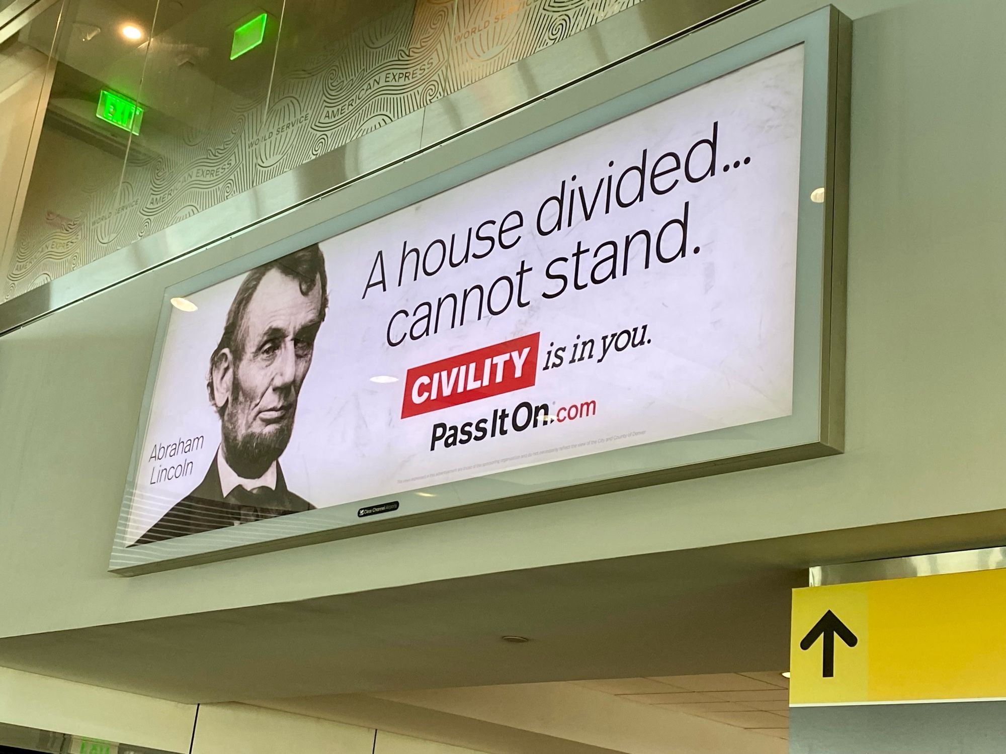 A lighted billboard inside an airport concourse with a portrait of Abraham Lincoln and the words, “A house divided cannot stand. Civility is in you. Pass it on.”