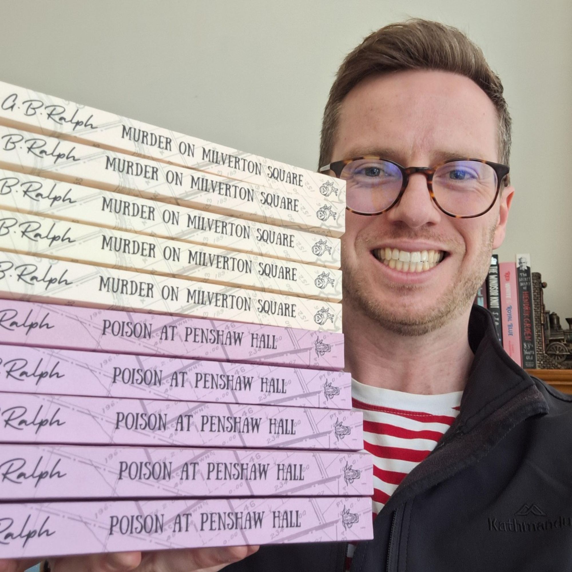 G B Ralph author selfie with stack of Murder on Milverton Square and Poison at Penshaw Hall paperbacks