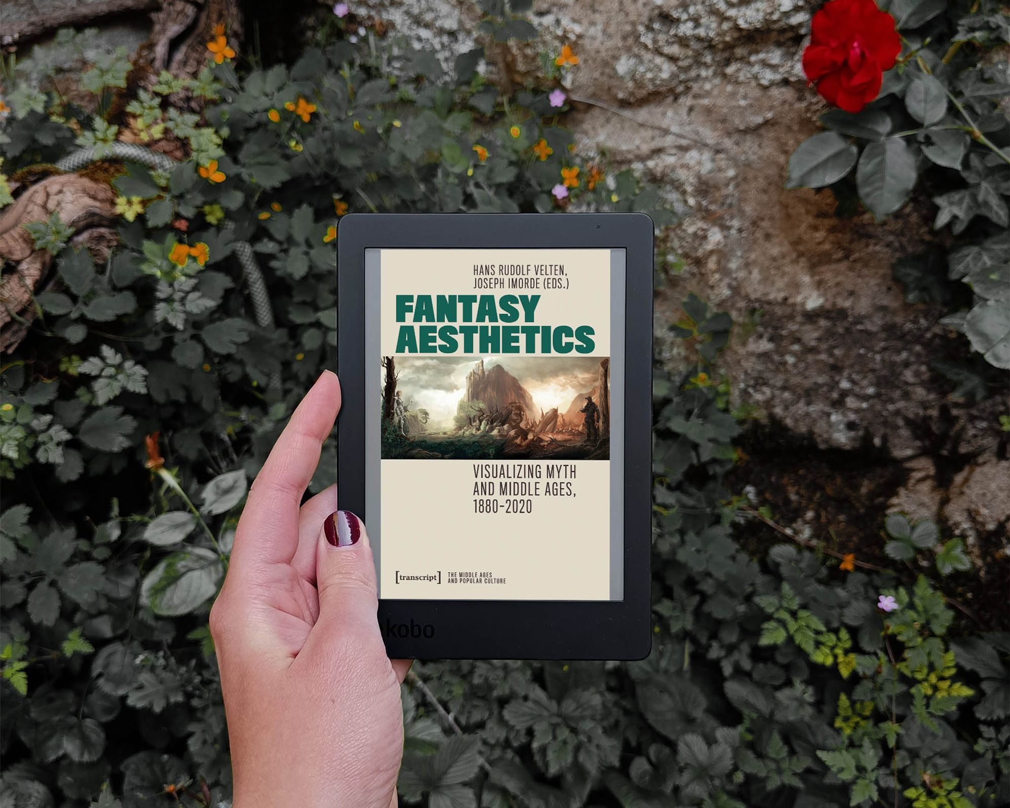 a white hand holds an e-reader showing the cover of the book in front of a stone wall covered in greenery.