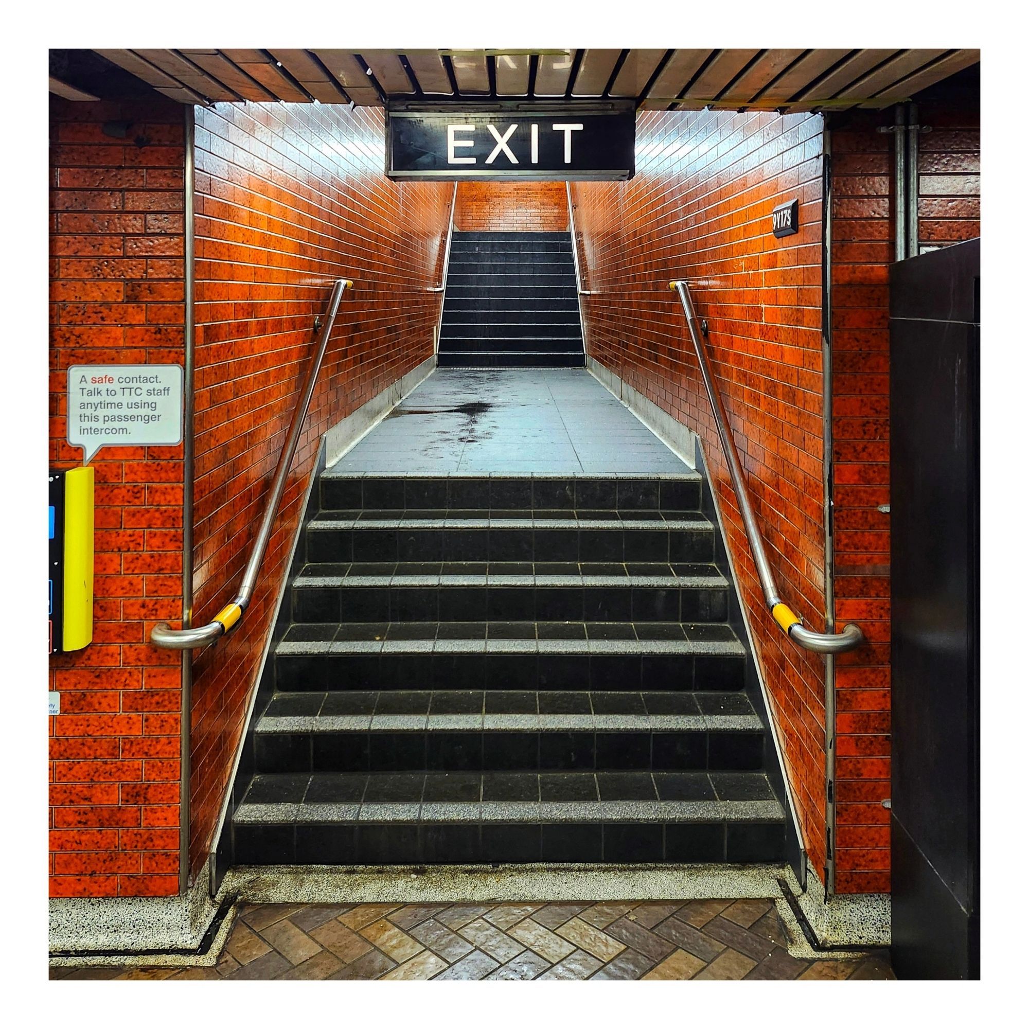 A staircase surrounded by orange tiles headed from Queen Subway Station to Yonge Street in Toronto Ontario