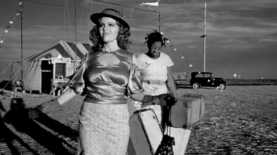 Madeline Kahn ('Trixie Delight') swans around grinning in a hoochie outfit while her long-suffering assistant Imogene (P.J. Johnson) struggles to carry her luggage in the background