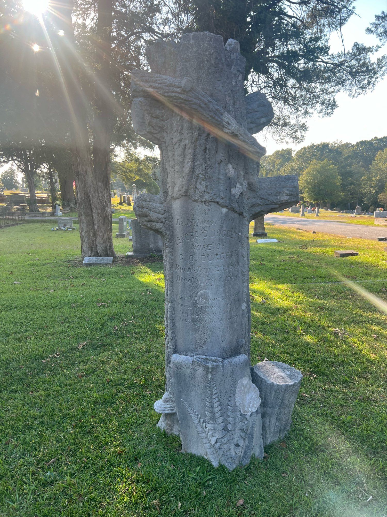 A granite tombstone shaped like a tree stump with engraved and cut ferns, lily and mushrooms for rustic motif. 