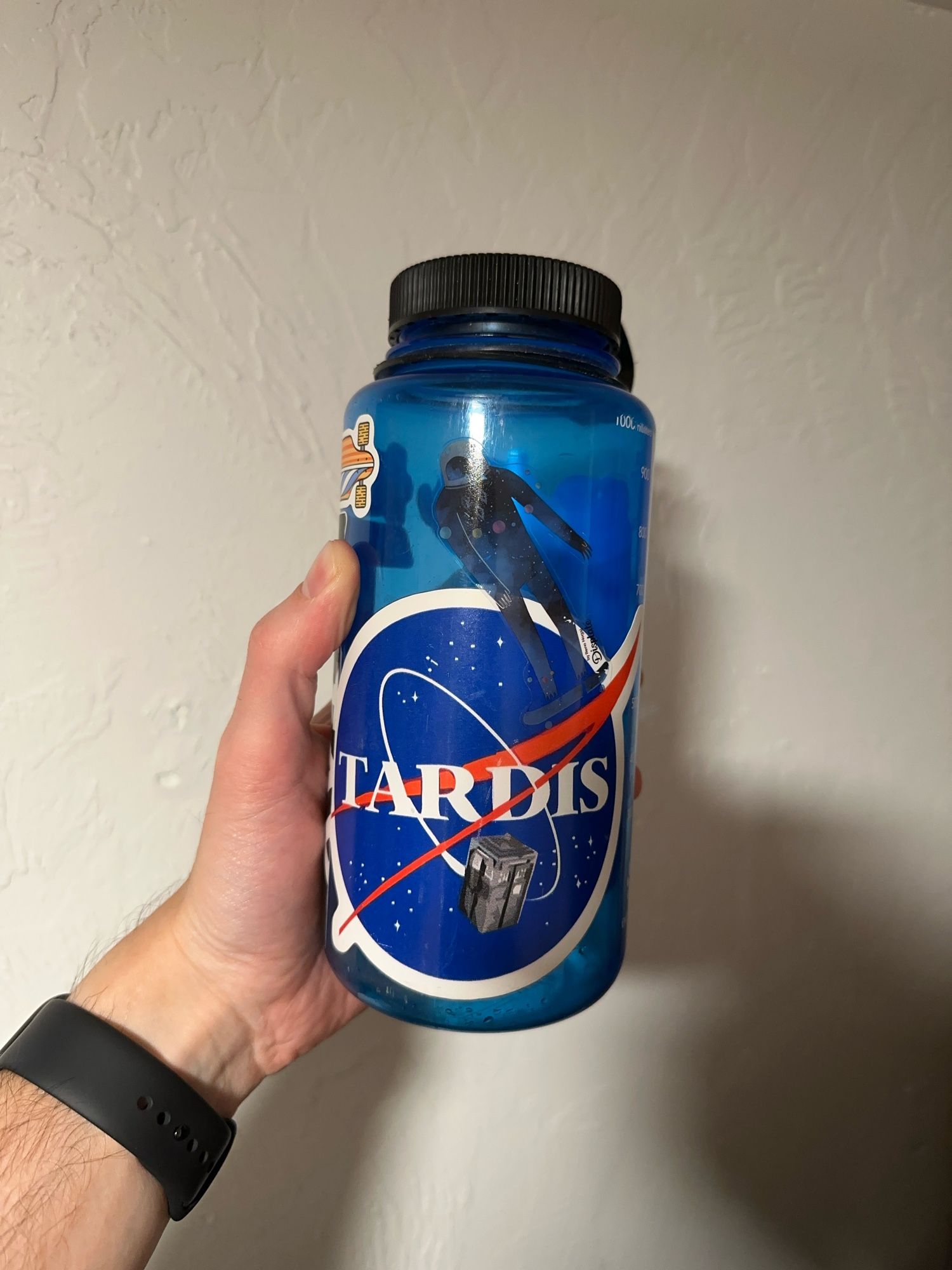 Photo of a water bottle, blue with a prominent tardis sticker made to look like a nasa logo.