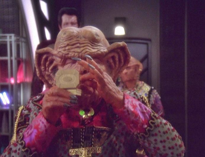 DS9 scene. Grand Nagus Zek enjoys a pinch of Hupyrian beetle snuff while Maihar'du and Moogie look on.