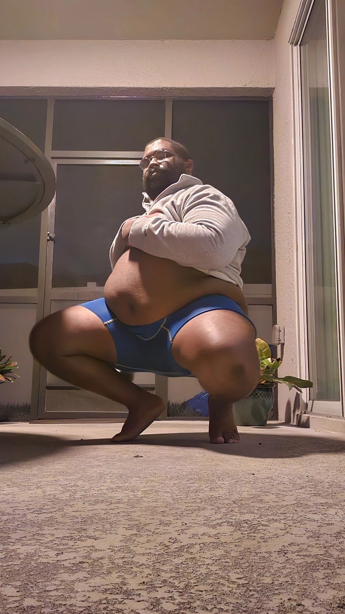 Me squatting in my empty back patio, belly showing. Gray top, blue undies