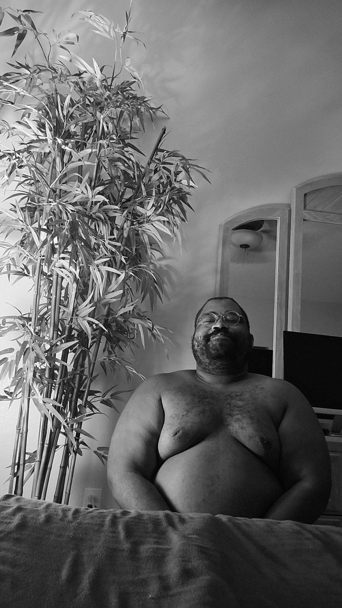 A B&W photo of me, next to some bamboo, shirtless