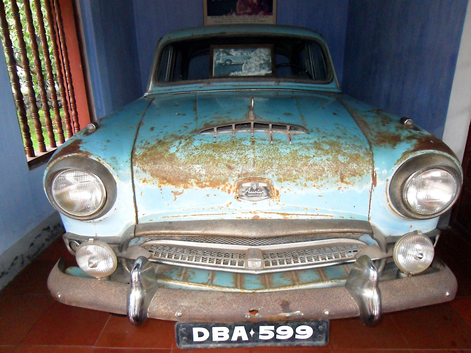 Picture of an old rusty blue car inside an outbuilding