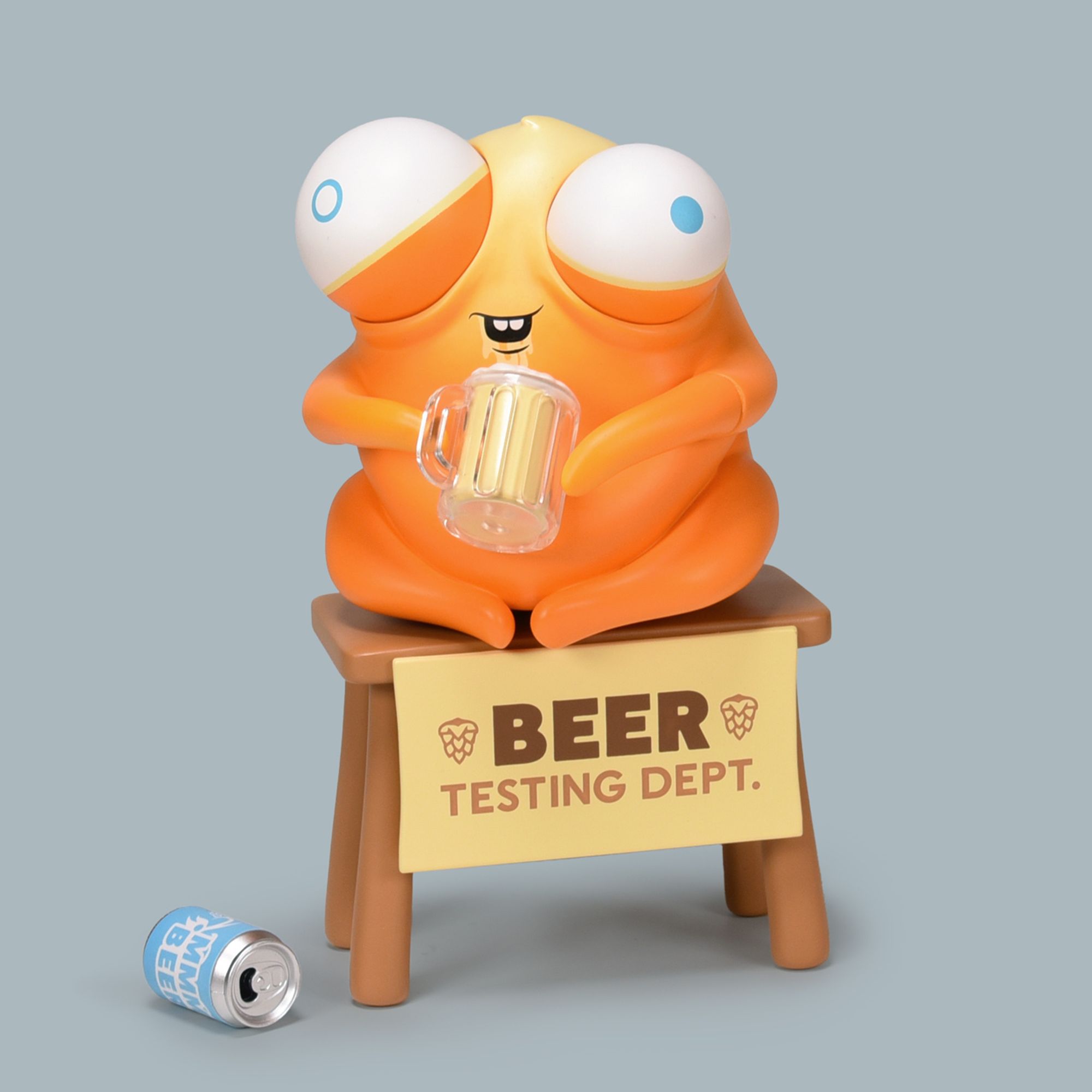 Picture of yellow bug-eyed creature sitting on a table holding a mug of beer, toy by Andrew Bell