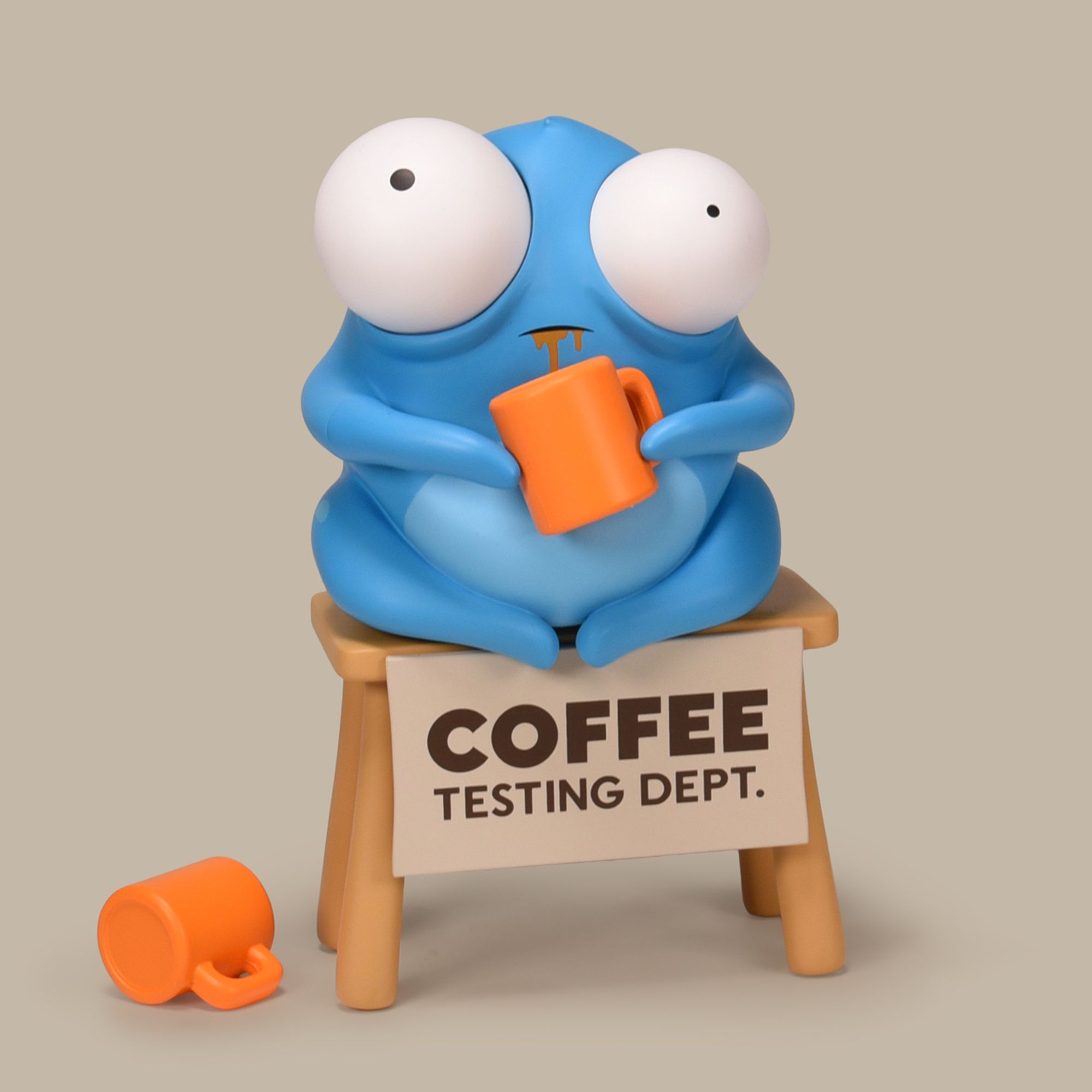 Picture of blue bug-eyed creature sitting on a table with a mug of coffee, toy by Andrew Bell