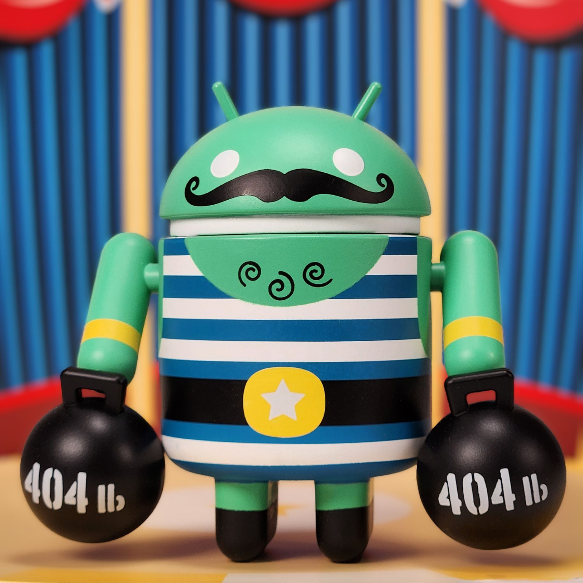 Strongman Android figure with moustache in striped leotard holding 404 lb weights