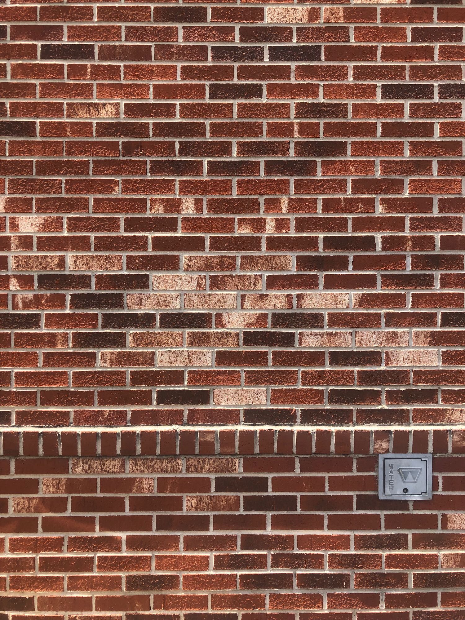 Brick wall with assortment of shades of red. A horizontal set of ‘ends’ separates the bottom fourth from the rest