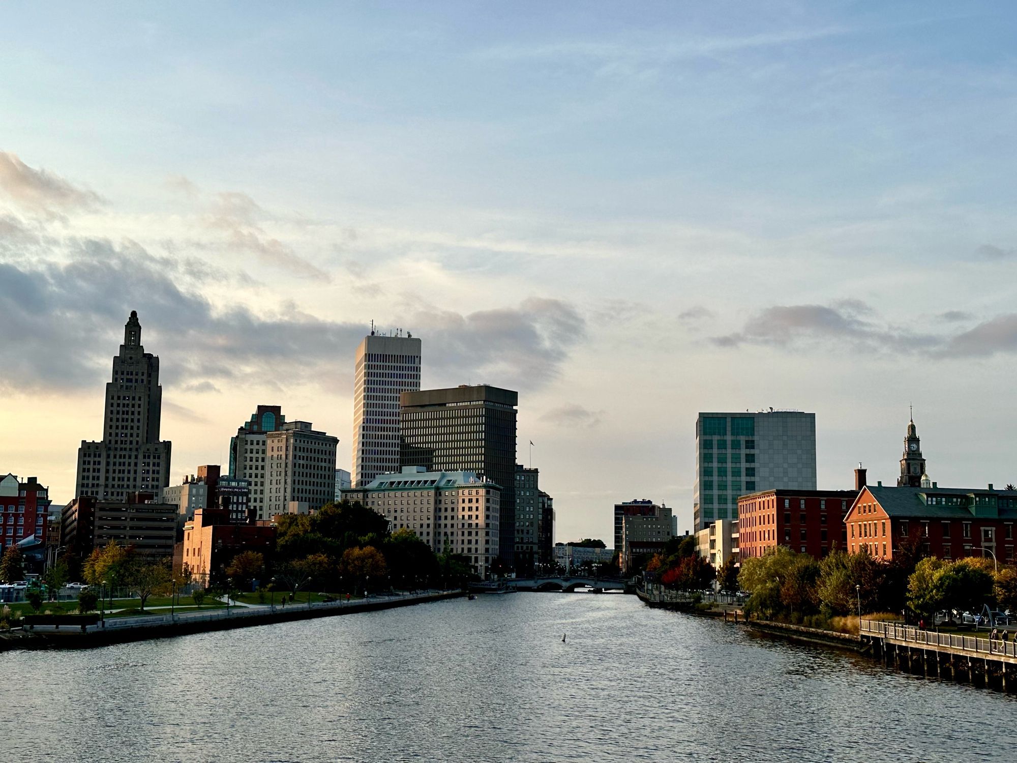 Photograph of the city skyline in Providence, Rhode Island about an hour before sunset. The view is from the pedestrian bridge, overlooking the river.